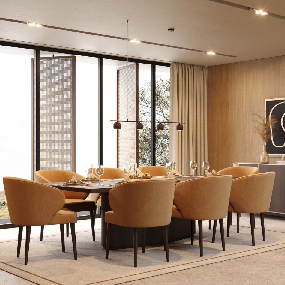 The Fortune Chairs define the space with their enveloping arms and deep, comfortable backrest, arranged around a rectangular table beneath a linear pendant light. Their caramel upholstery and dark oak legs bring warmth and natural texture to the minimalist room, complementing the wood paneling and curated decor. The scene reflects sculptural modern furniture design, harmonious contemporary decor and the calm clarity of minimalist interiors.