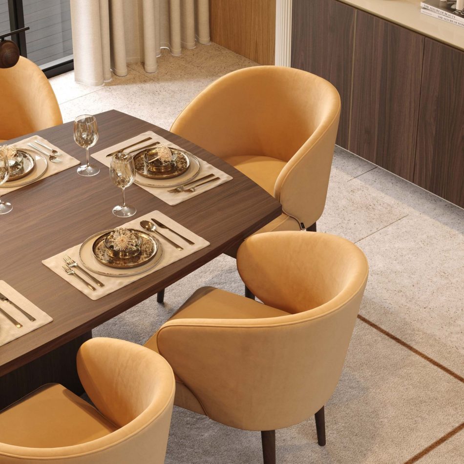 The Fortune Chairs sit around a wooden dining table set for a luxurious meal, their curved arms and deep back offering comfort and support. The yellow upholstery enhances the intimate, cosy atmosphere, while the dark oak legs introduce an organic, grounded note. The warm materials and soft lighting create a serene dining environment shaped by expressive modern furniture design, contemporary decor and understated minimalist interiors.
