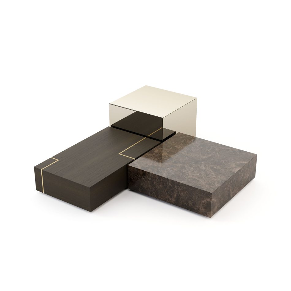 The Fortune Coffee Table set is shown as a geometric arrangement of three blocks: dark wood with a gold accent, warm brown marble, and a mirrored metallic cube. Their contrasting textures create a harmonious, minimalist structure that feels both robust and elegant. The design reflects sculptural contemporary furniture, enriched by the presence of luxury home furniture and defined by precise design details.