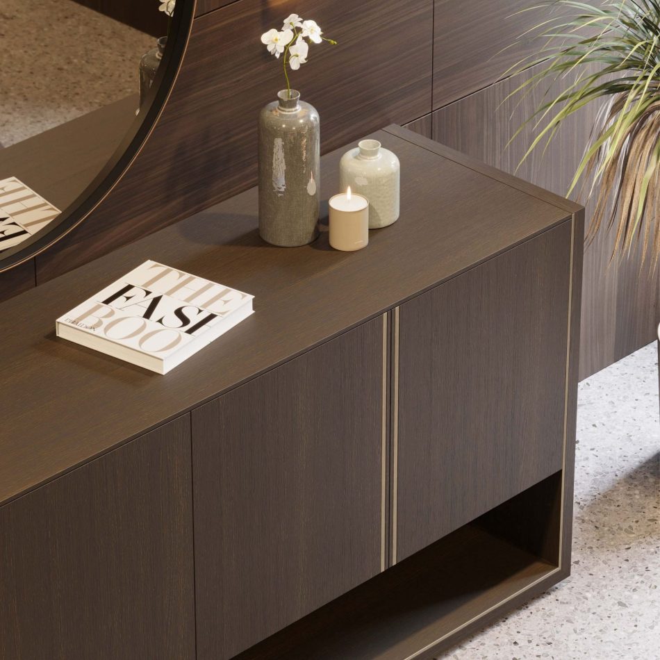 The Fortune Sideboard is shown in close view, its matte oak doors and brass‑lined contours creating a robust, elegant presence. Styled with ceramic vases, a candle, and a sculptural plant, the piece reflects casegoods furniture, warm interior design inspiration, and the understated glamour of luxury home furniture.