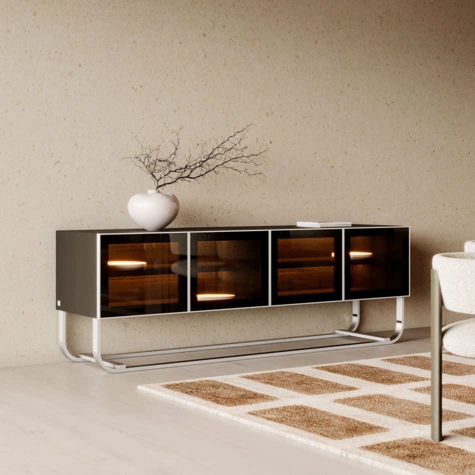 The His Sideboard features a dark, minimalist structure elevated on curved metallic legs, with bronze‑glass doors that reveal softly illuminated shelves inside. A white ceramic vase with bare branches and a closed book rest above the piece, blending luxury dining room furniture, subtle design details, and warm interior design inspiration.