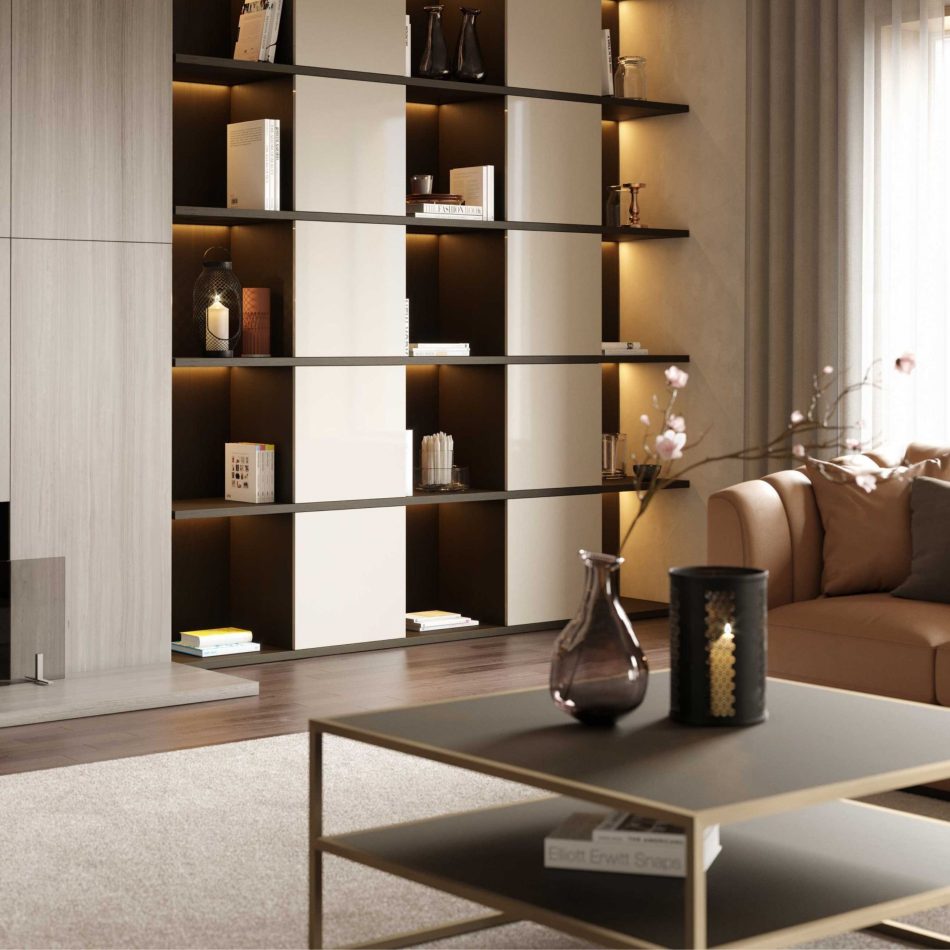 The Bridge Coffee Table, with its dark oak tops and bronze‑brass frame, sits at the center of a softly lit living room featuring a beige sofa and a built‑in shelving wall. Warm lighting highlights the table’s minimalist lines and layered décor. The space blends refined luxury home furniture with calm, textural living room architecture and a balanced sense of interior design inspiration.