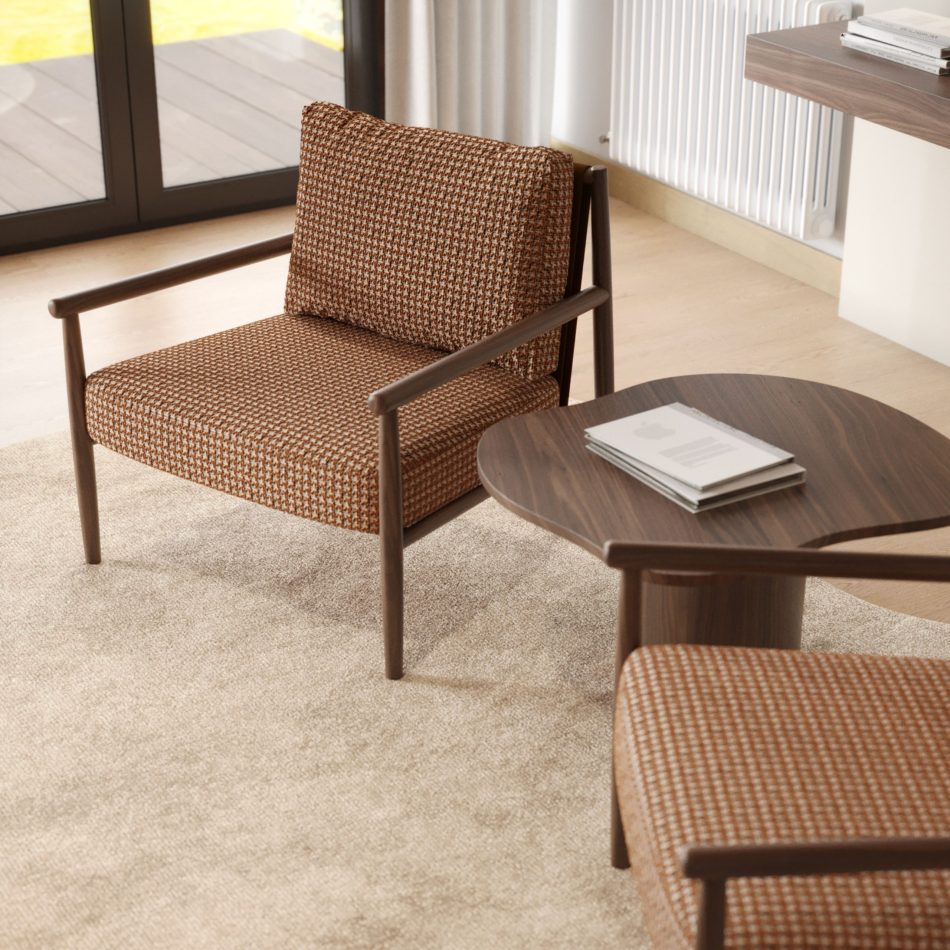 Close-up of the Landform Armchair in its rust houndstooth pattern upholstery beside a walnut side table stacked with magazines, natural light streaming in from garden doors, highlighting the furniture upholstey fabric and cozy scale of this living room furniture piece.