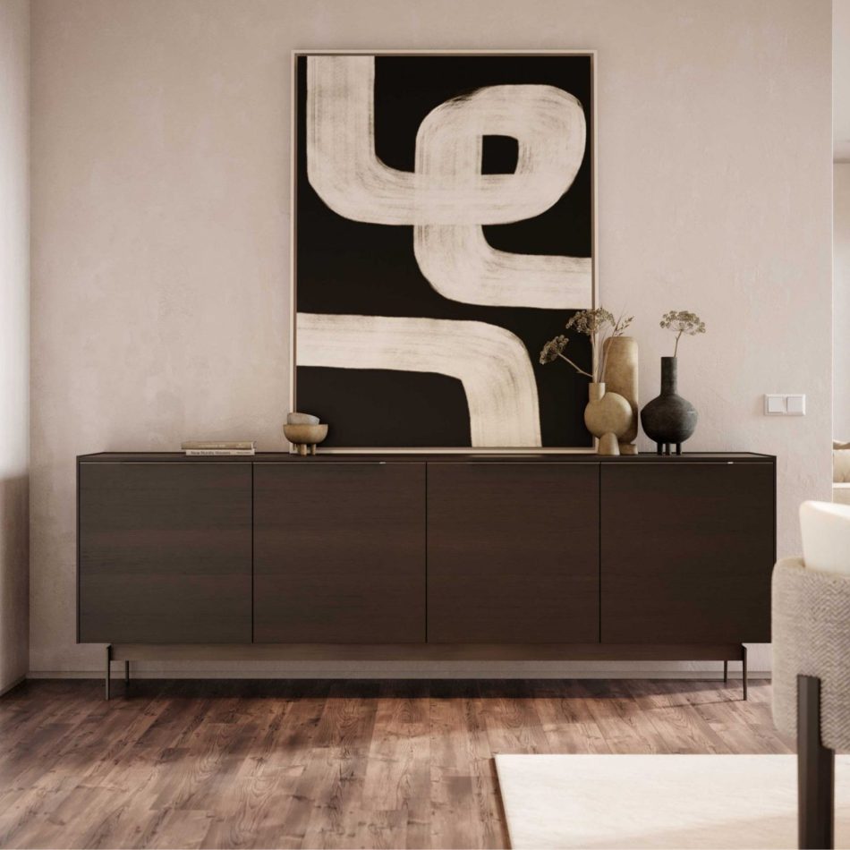 The Landform Sideboard stands against a soft neutral wall, its dark wood surface styled with ceramic vases and sculptural decor that highlight its clean, architectural lines. Above it, a bold black‑and‑white abstract painting adds contrast, while a glimpse of an upholstered chair softens the composition. This refined corner reflects the clarity of modern sideboard design, elevated by elegant casegoods furniture, and shaped to inspire subtle interior design inspiration.