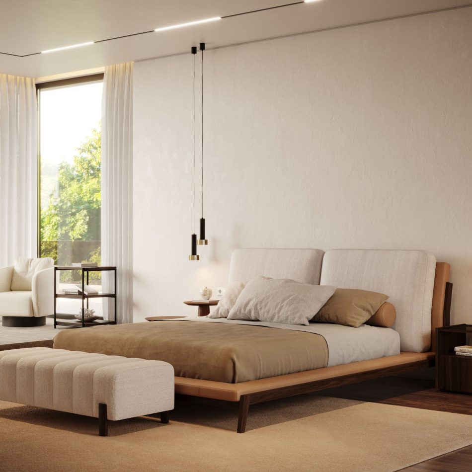 A bright bedroom with the Milos Bed set against a plastered wall, its headboard and leather-trimmed frame catching natural light from a tall window, with a matching bench, side shelving, and a soft armchair nearby. The bed's low profile and mix of fabric and leather bring a sober, modern character to the room, reflecting the kind of luxury master bedroom furniture suited to versatile decorative environments.
