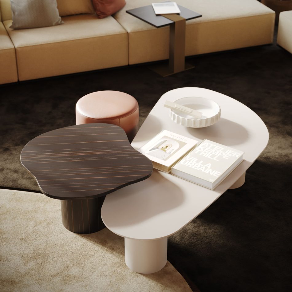 The Natur Coffee Table in a smooth white finish sits beside a dark wood table, styled with books and a sculptural bowl. A beige sectional, rust ottoman, and soft lighting frame the minimalist composition with calm warmth. The scene blends curated furniture for living room with sculptural modern furniture and subtle design details.