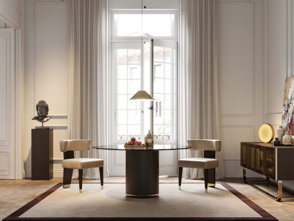 The Her Round Dining Table sits at the center of a dining room, featuring a sculptural dark base and a marble top. Two upholstered chairs frame the table, while tall curtains and French doors fill the space with soft daylight. The surrounding décor, including a Buddha sculpture and a warm circular lamp, creates a atmosphere shaped by luxury dining room furniture, layered design details, and gentle interior design inspiration.