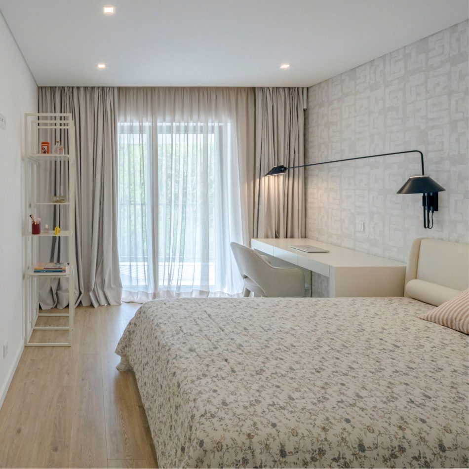 A serene bedside corner featuring the Santorini Night Table, its clean form supporting a warm, minimal lamp. The edge of the bespoke Porto Bed appears in soft neutral tones, reinforcing the room’s calm identity. Light, shadow, and subtle blue accents create a refined sense of modern bedroom design.