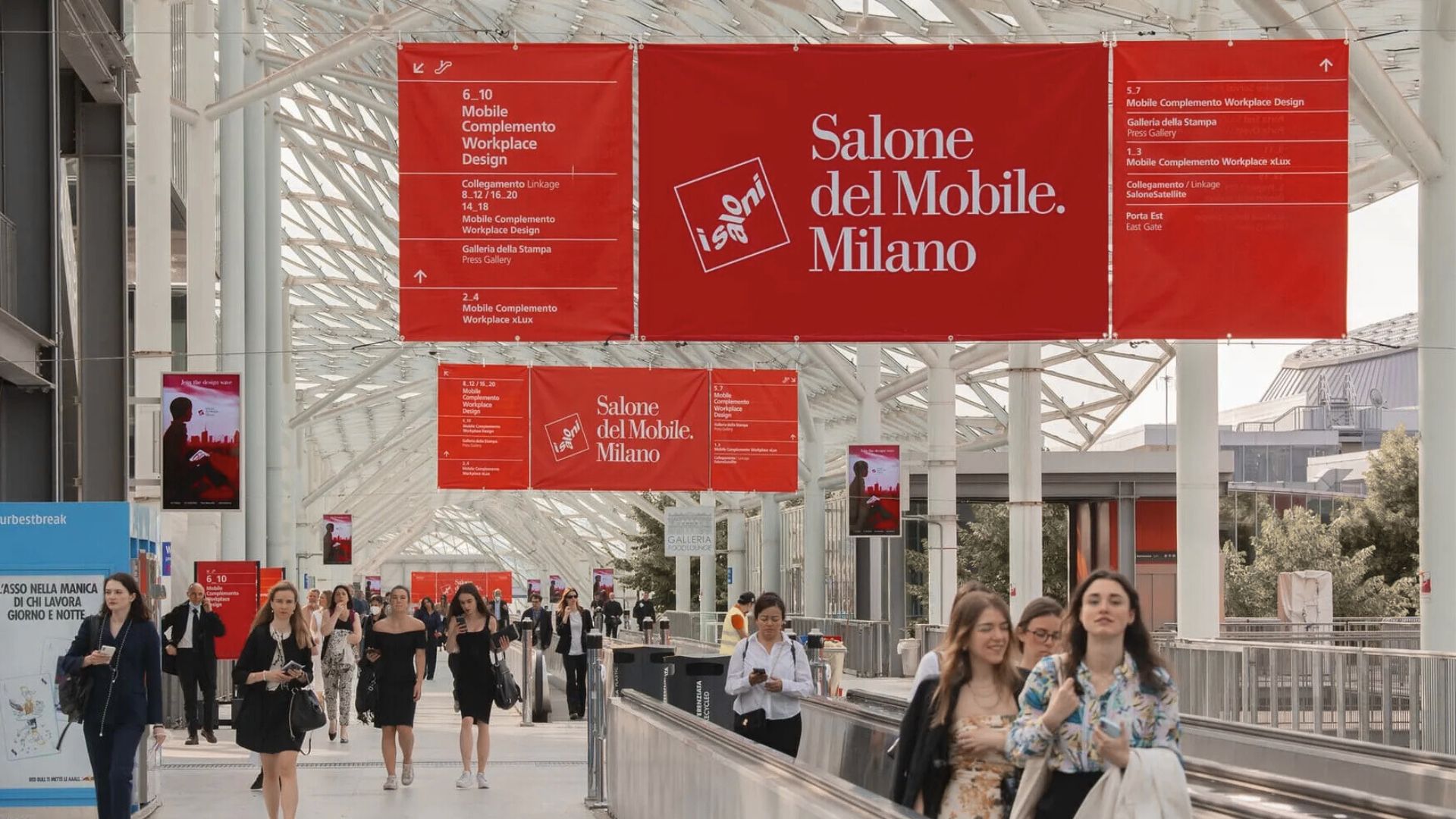 Main entrance of the Salone del Mobile in Milan, with people arriving at the venue.