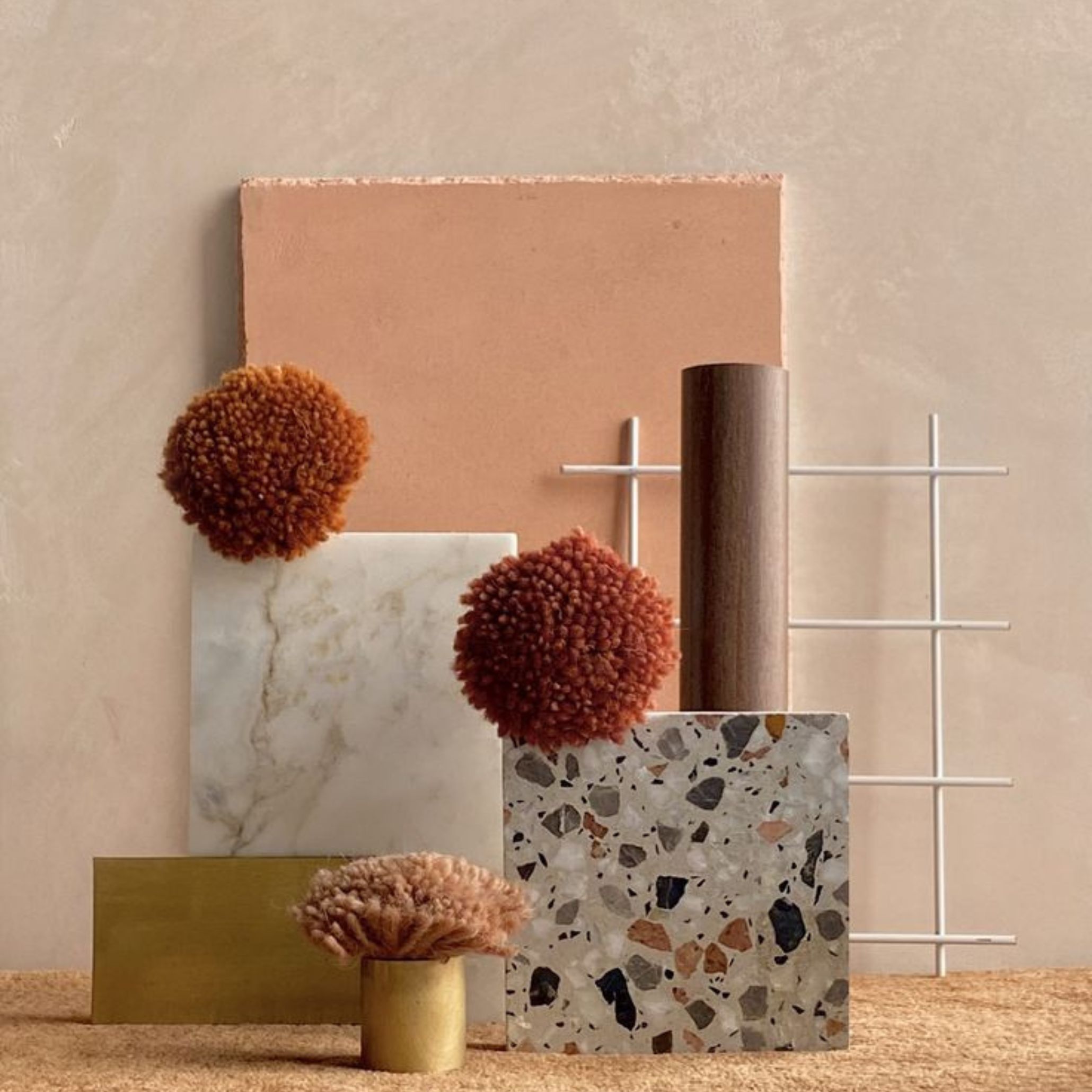Warm-toned mood board with terrazzo, marble, brushed brass, wood, and textured textiles, demonstrating a balanced material palette.
