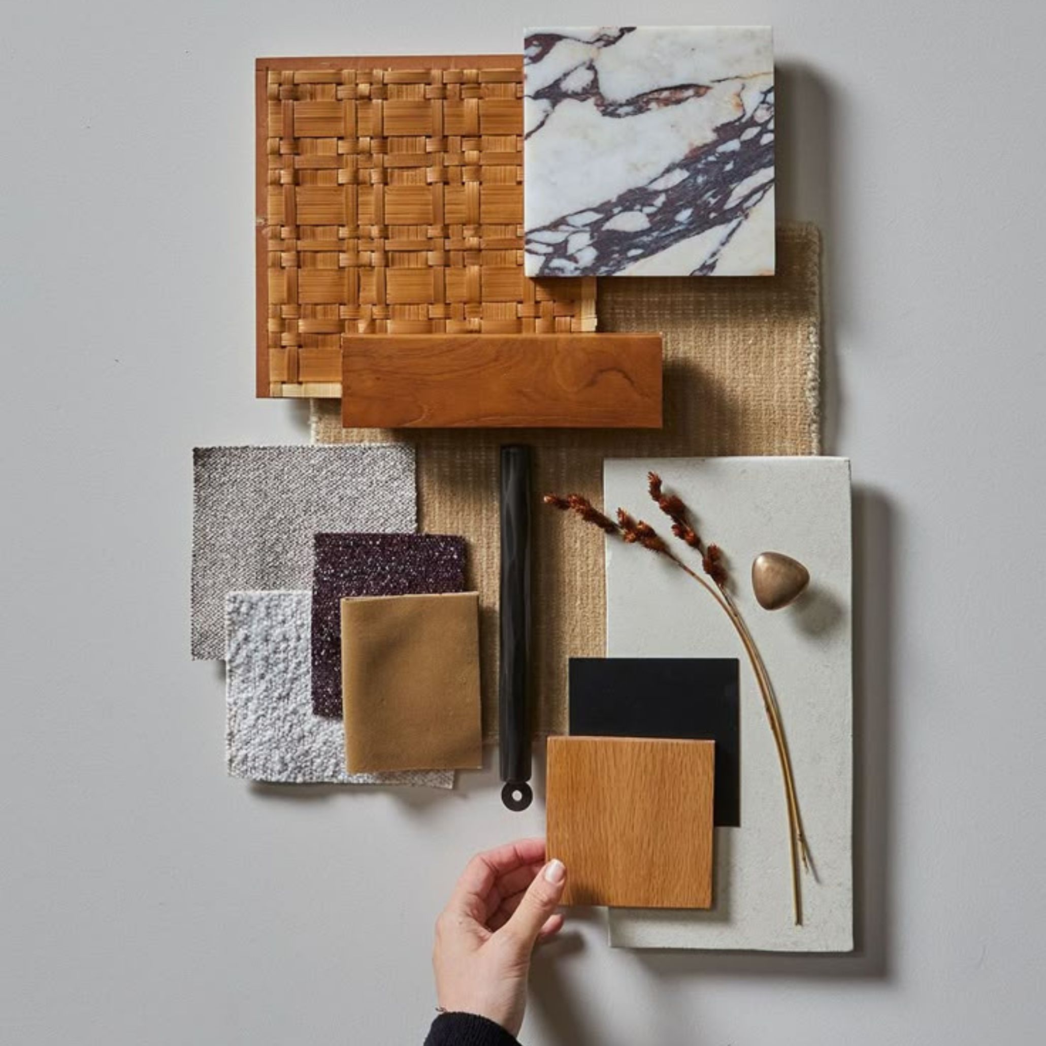 Mood board showing fabric swatches, polished stone, and wood samples in earthy tones.