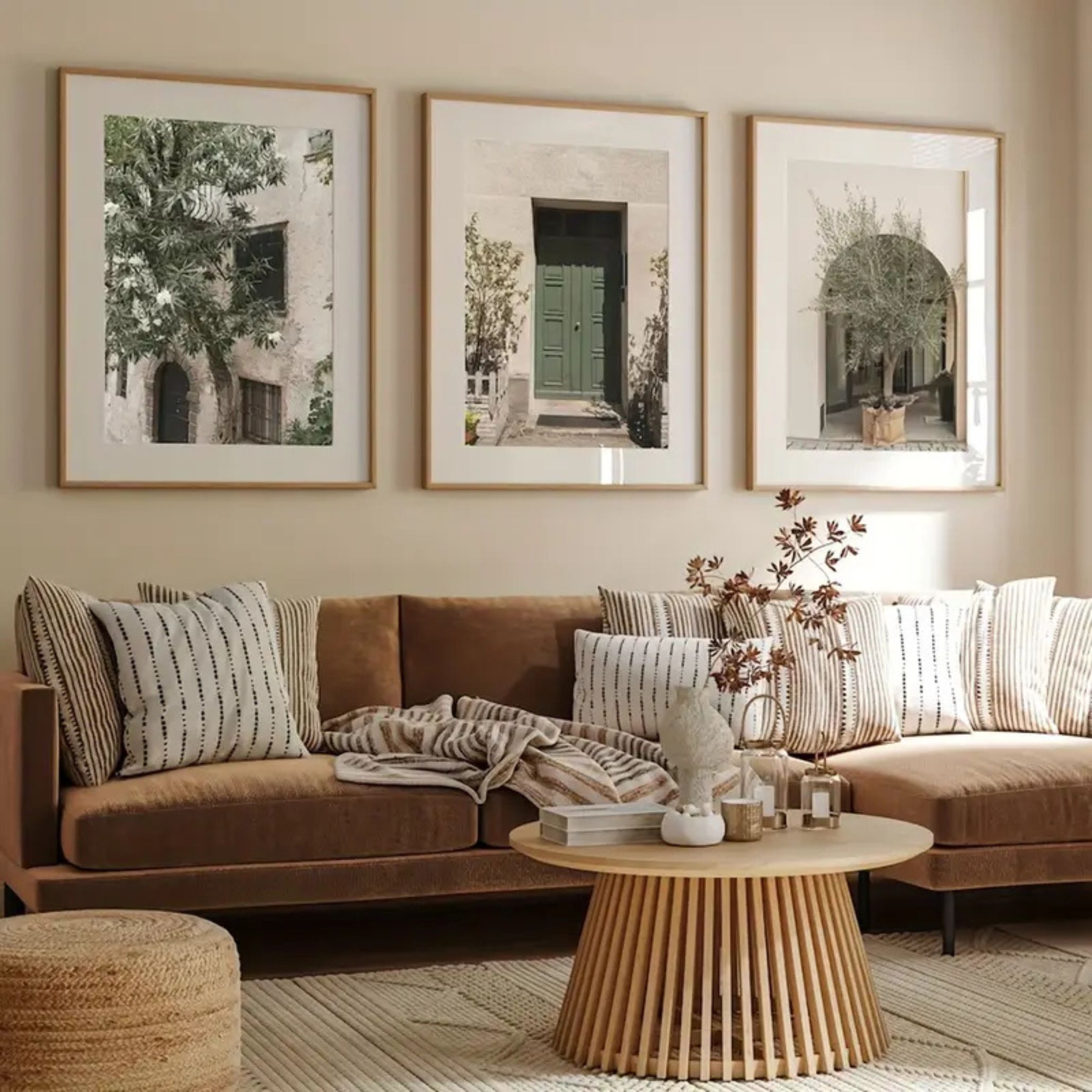 Cozy living room featuring a brown velvet sofa, striped cushions, a round slatted wood coffee table, and framed nature photography, combining warm textiles and natural elements.