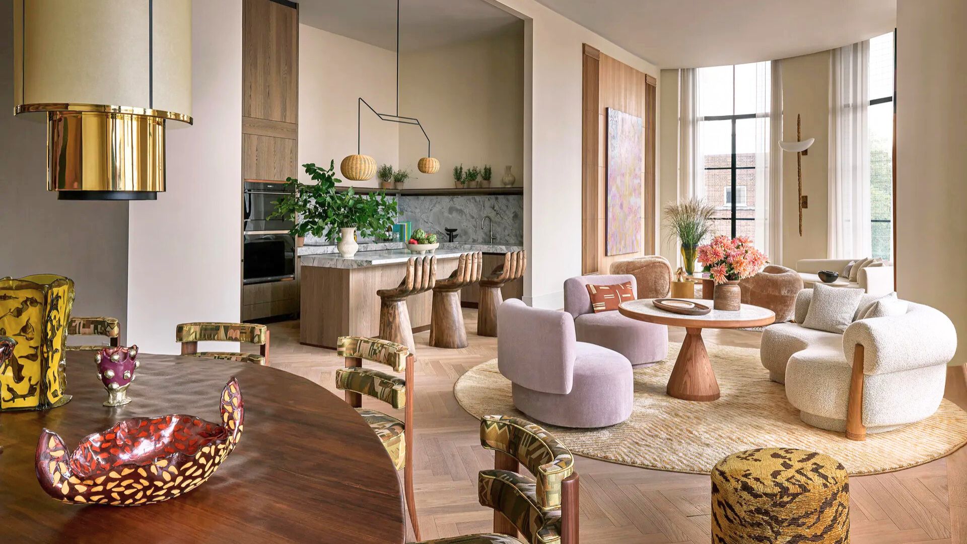 Eclectic open space combining marble, velvet, brass, and wood, with sculptural furniture and bold colors, showcasing a playful mix of materials and styles.