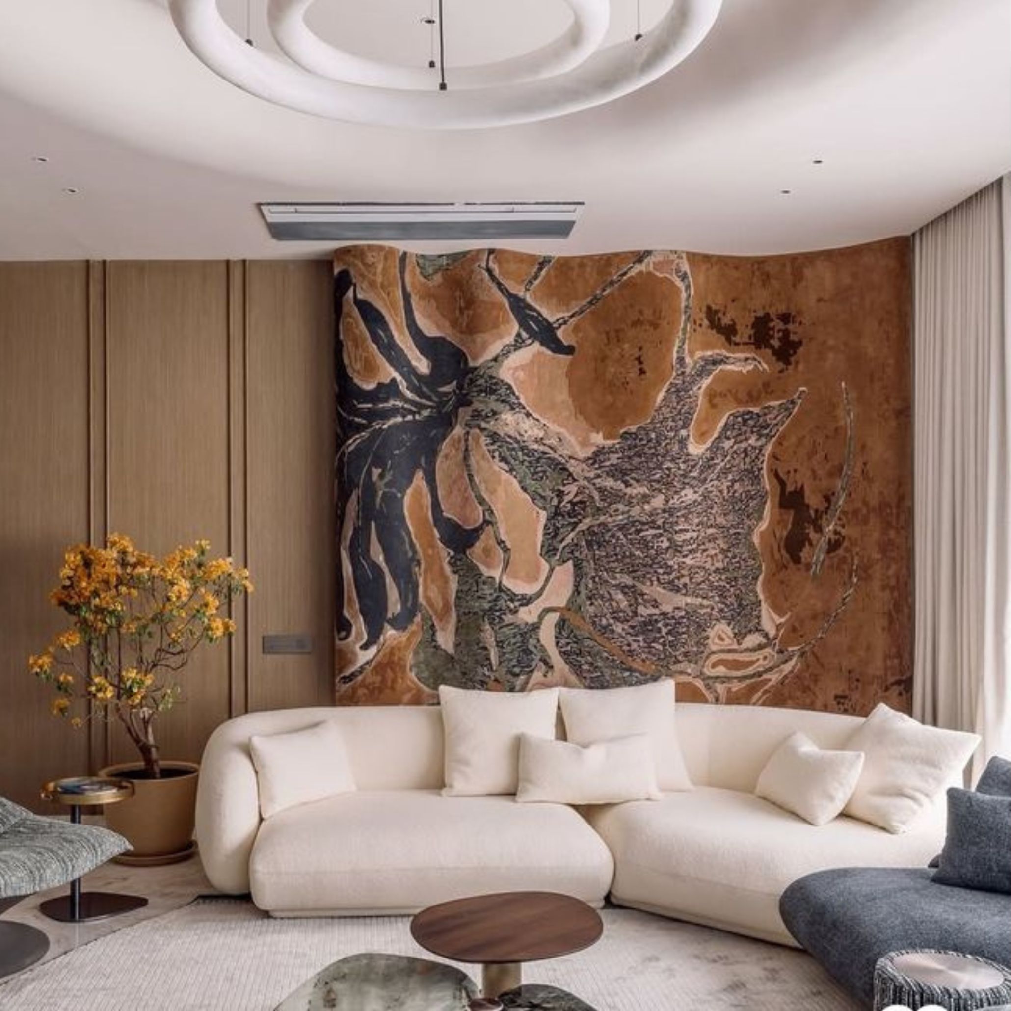 Artistic living room with a bold abstract wall tapestry, curved cream sofas, and natural wood furniture, blending art, textiles, and design.