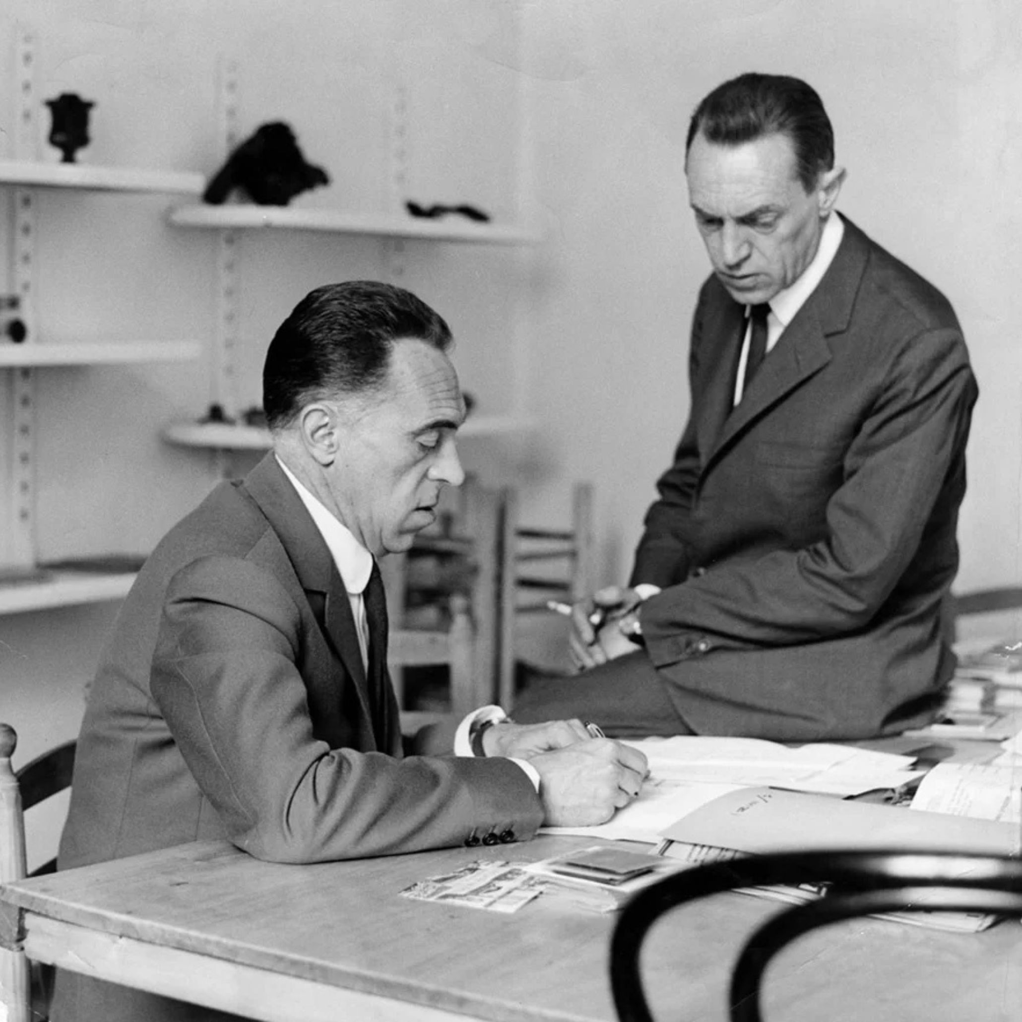 Achille and Pier Giacomo Castiglioni working together at a desk, captured in their design studio in black and white.