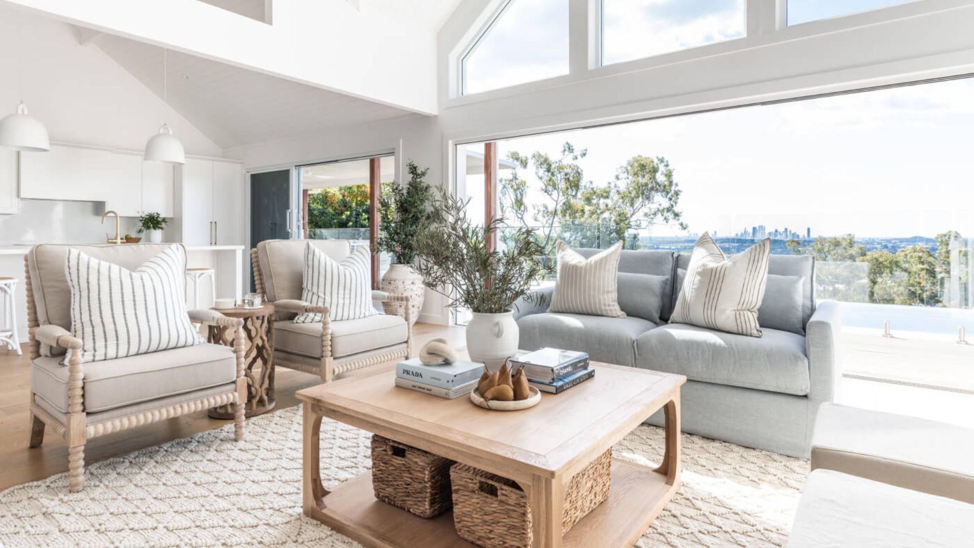 Bright living room styled in Contemporary Coastal Interior Design with neutral tones, natural elements, soft textiles and large windows framing a panoramic ocean view.