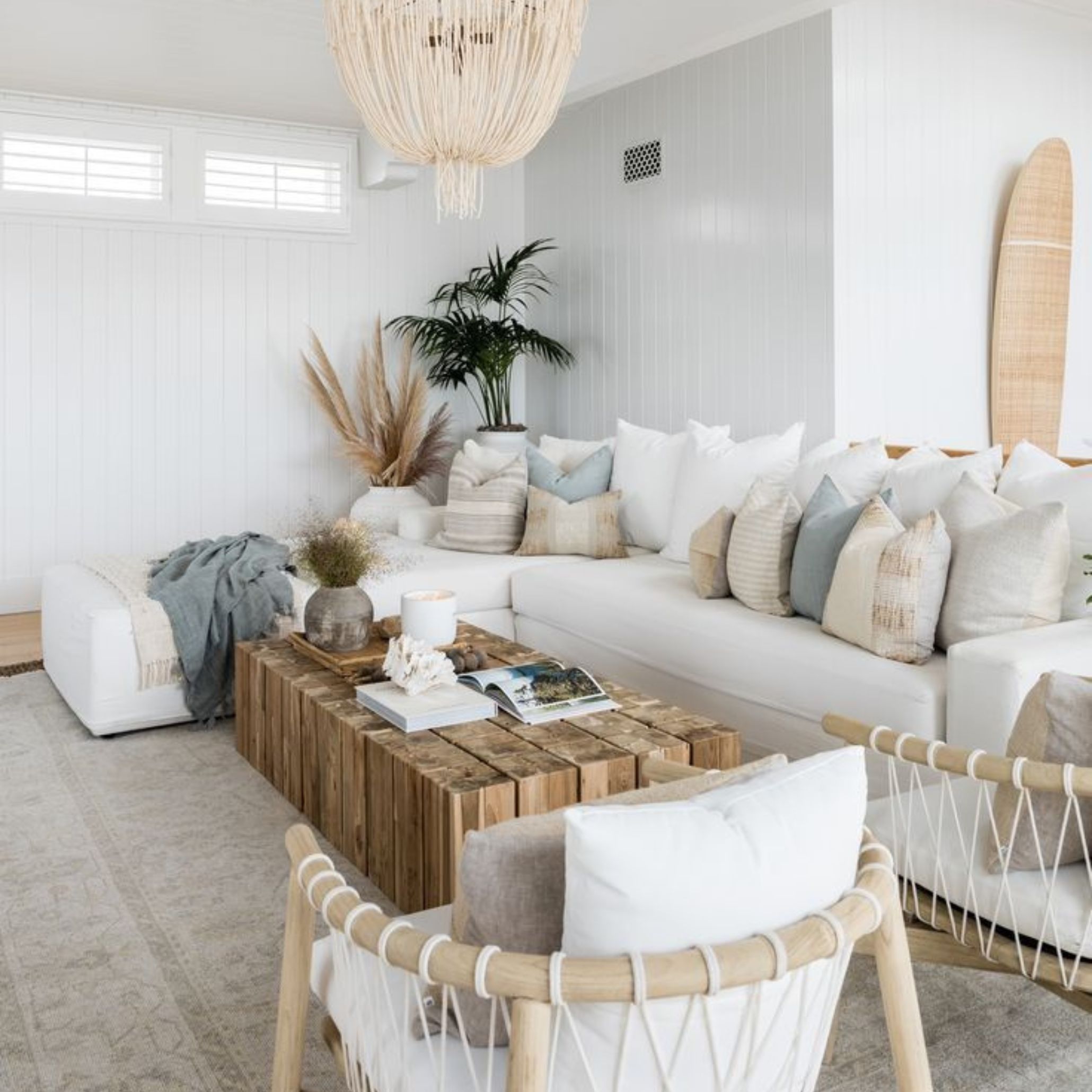 Relaxed coastal lounge with a white sectional sofa, wooden coffee table, textured cushions and neutral tones, reflecting the harmony and calm of Modern Coastal Interiors.