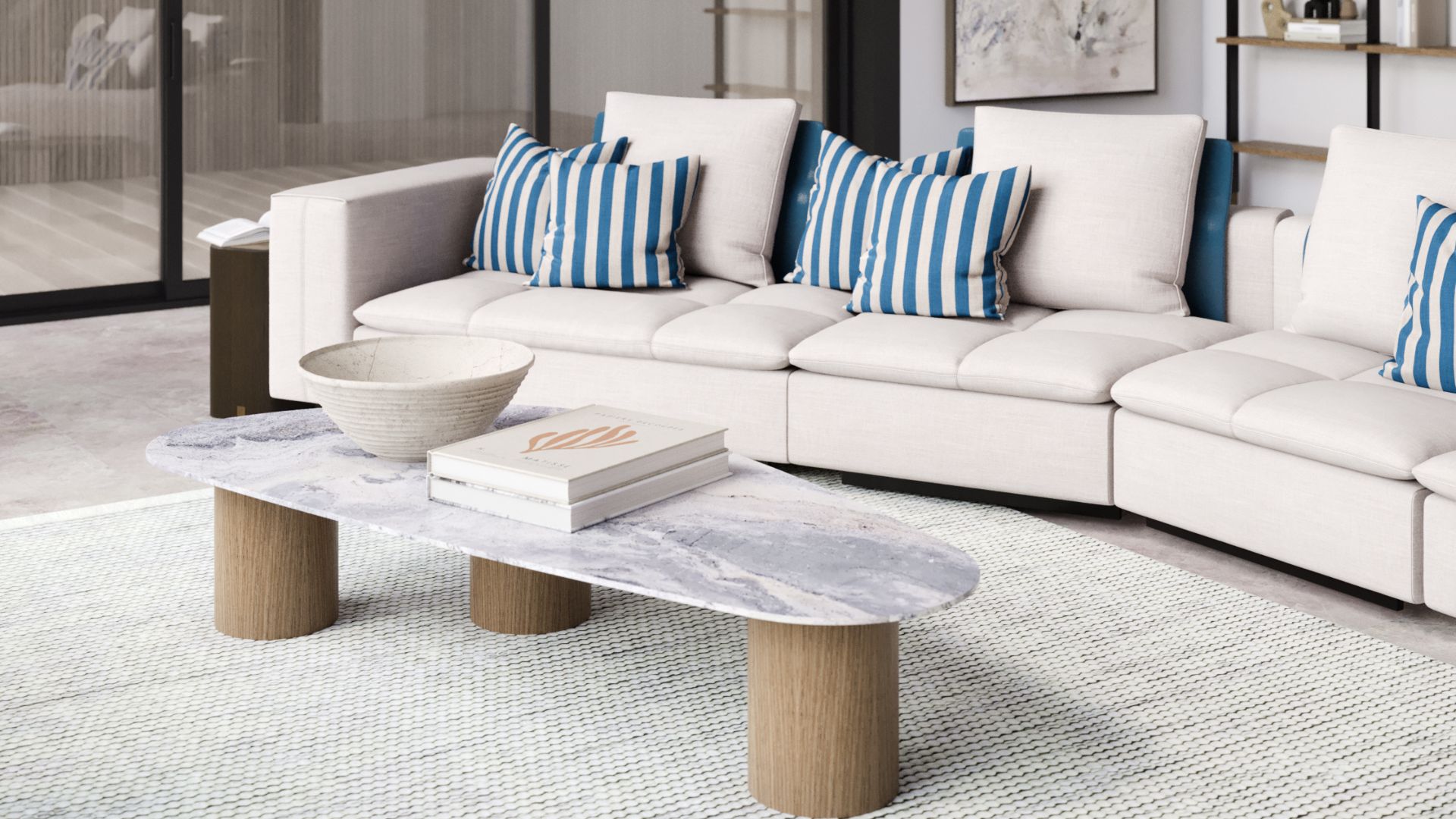 A close-up of the Hamptons Style House living room showcasing the Margem Sofa, upholstered in neutral fabric with contrasting blue back cushions and pillows. In front, the elegant Natur Coffee Table with solid wood bases and a River Blue marble top adds a luxurious and organic touch, enhancing the contemporary coffee table style of the space.