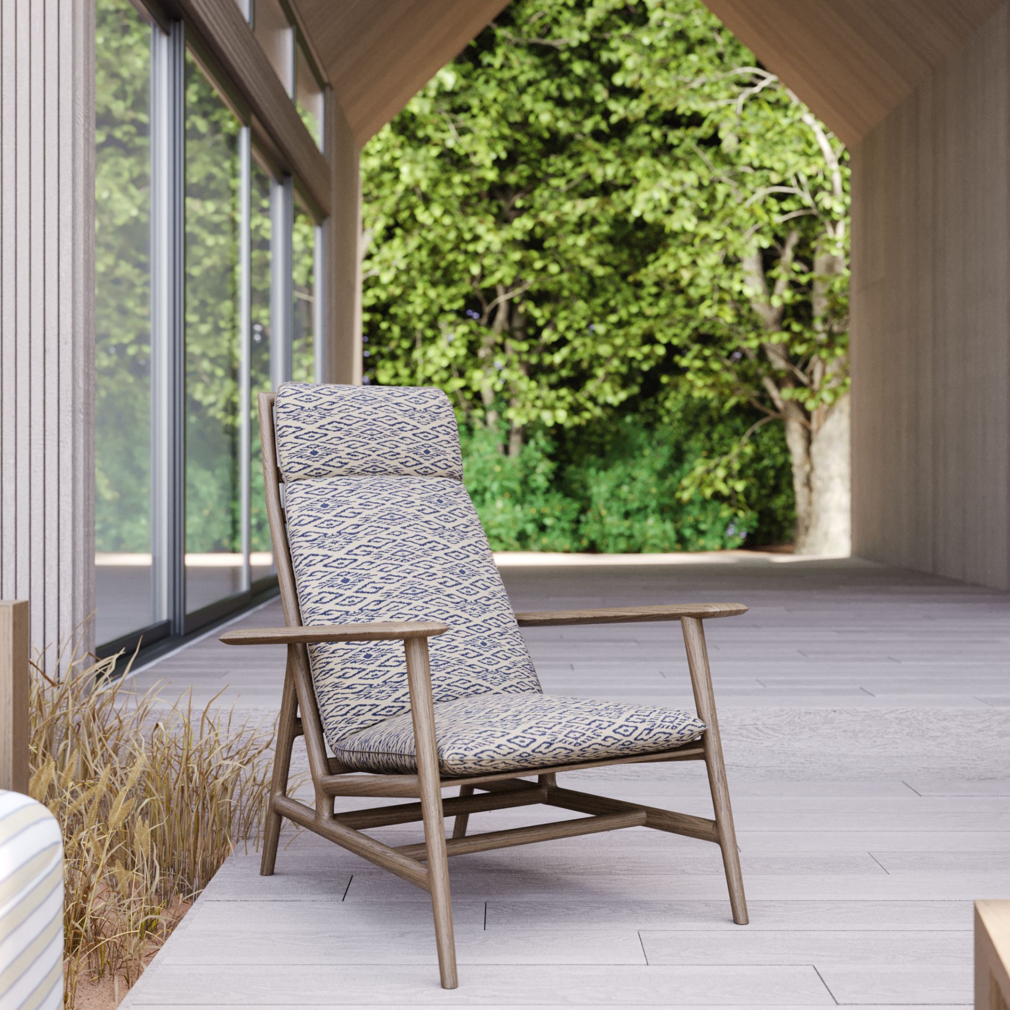 A detailed view of the Ripa Armchair in the Hamptons Villa’s outdoor space, upholstered in a beige and navy blue patterned fabric. Set against a tranquil natural backdrop, this elegant piece from Stylish Club’s outdoor selection embodies the timeless sophistication and relaxed Hamptons Style House exteriors.