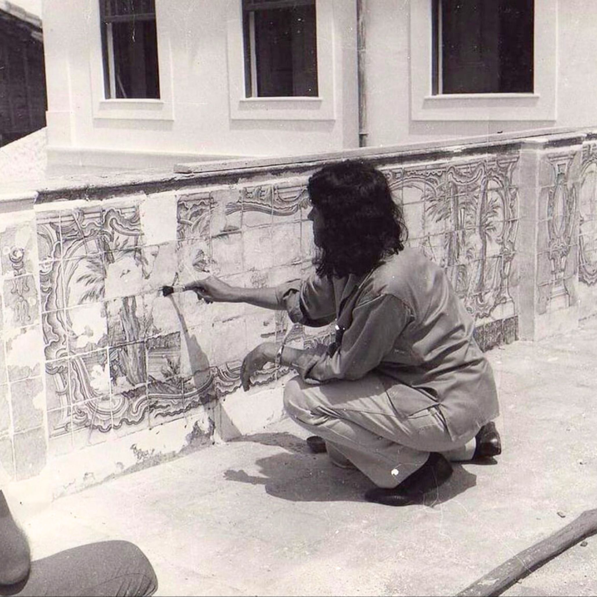 Lina Bo Bardi painting a wall, embodying her hands-on approach to architectural creation. This moment reflects her commitment to crafting spaces with intention, bridging art, architecture, and human expression.