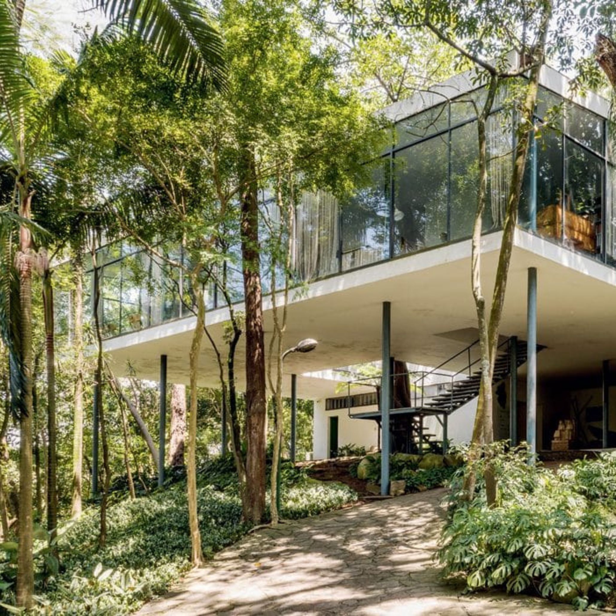 Main perspective of Casa de Vidro by Lina Bo Bardi, immersed in São Paulo’s greenery. This contemporary residence, suspended above the ground, illustrates her dedication to Brazilian modern architecture that harmonizes built space with the natural environment.