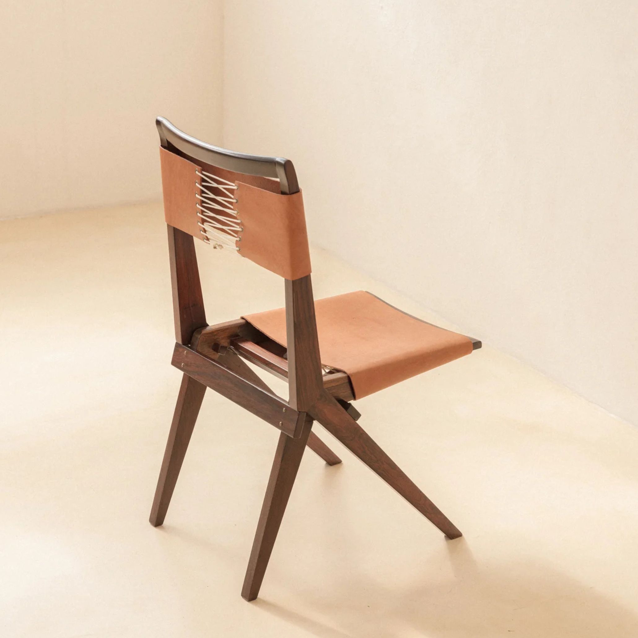 Photograph of MASP Chairs designed by Lina Bo Bardi, featuring a wooden frame and camel leather upholstery. These chairs embody her dedication to practical, elegant furniture design that complements architectural space without overpowering it.