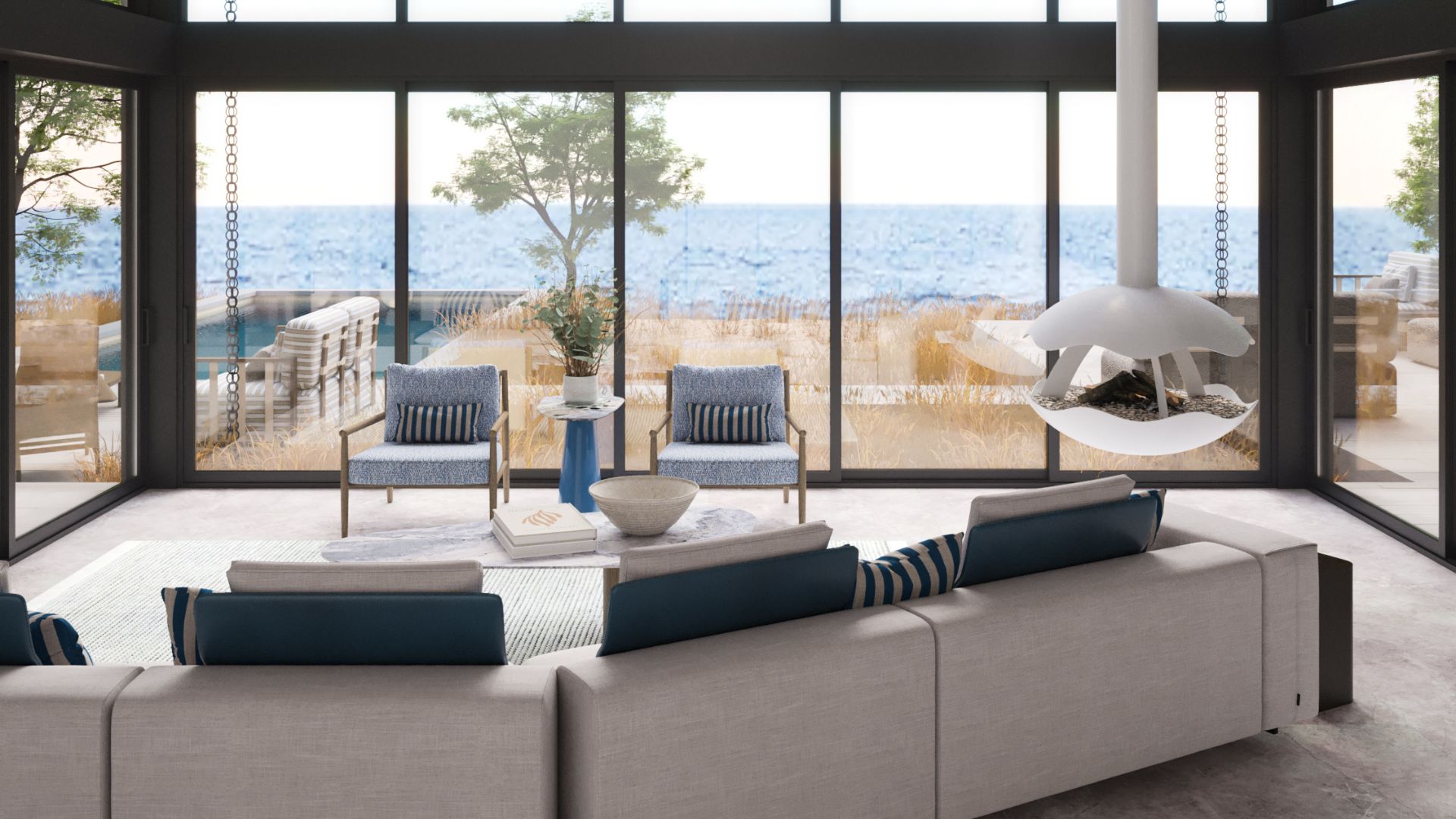 The stunning Hamptons Villa, showcasing the essence of the Nancy Meyers Aesthetic with modern furniture in warm neutral tones, expansive glass walls framing the sea, and a sculptural suspended fireplace. This space harmoniously blends contemporary Hamptons interior design with soft sophistication and light-filled serenity, capturing the spirit of luxury living by the beach.