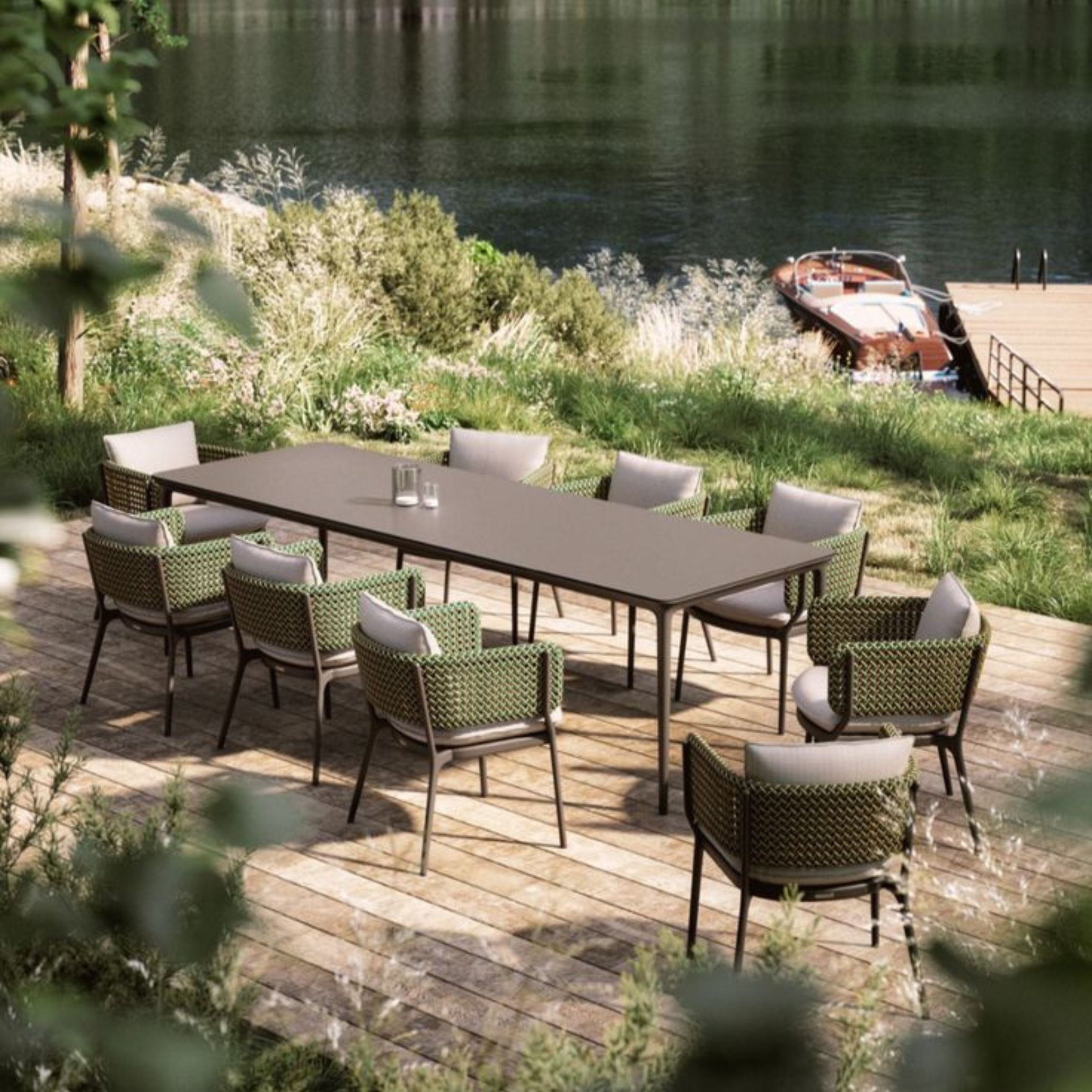 A refined lakeside dining area featuring a sleek modern table surrounded by ten chairs with green woven backs and soft grey cushions. Placed on a wooden deck near a vintage boat, this tranquil setting captures the essence of eco-conscious luxury and outdoor living in harmony with nature.