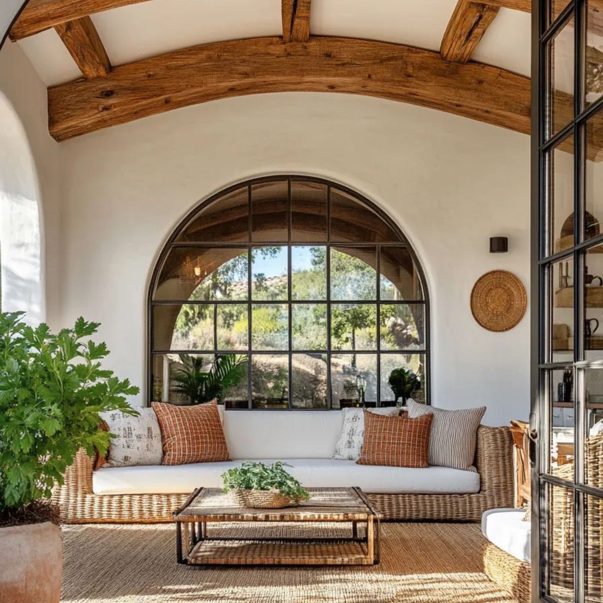 Inviting outdoor seating area framed by stone walls and terracotta floors, featuring warm-toned cushions and aged wood furniture. The scene evokes the relaxed elegance of Italian country living and highlights Tuscan design’s emphasis on natural materials, warm colours, and a seamless indoor-outdoor lifestyle.