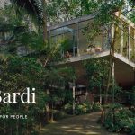 Banner showcasing architect Lina Bo Bardi alongside a striking image of Casa de Vidro, her iconic glass house nestled in the tropical landscape of São Paulo. The modernist structure, elevated on slender stilts, seamlessly blends transparent architecture with nature, reflecting Bo Bardi’s visionary approach to design and her deep connection to Brazilian culture.
