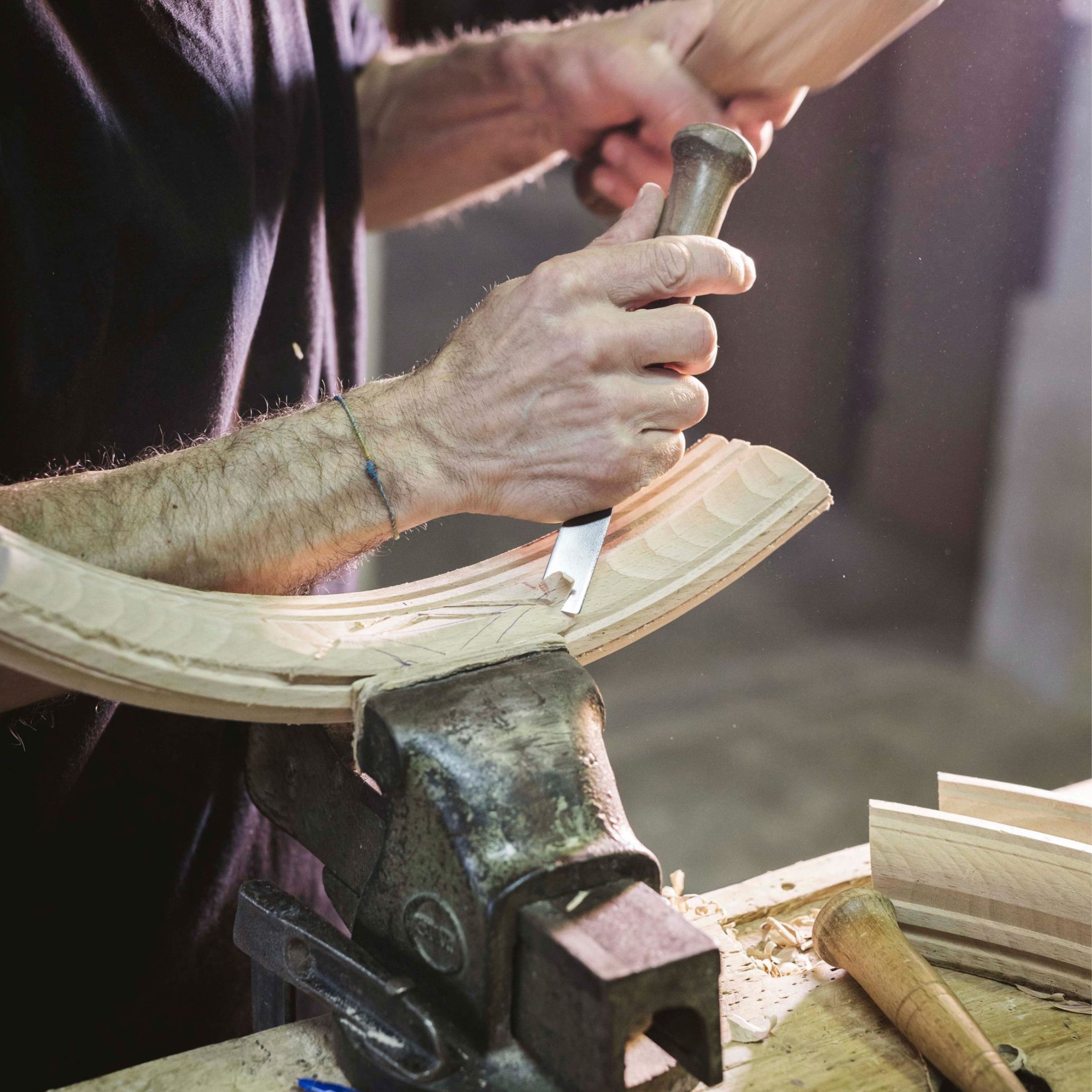 A craftsman working with wood, showcasing traditional woodworking techniques and detailed furniture craftsmanship.