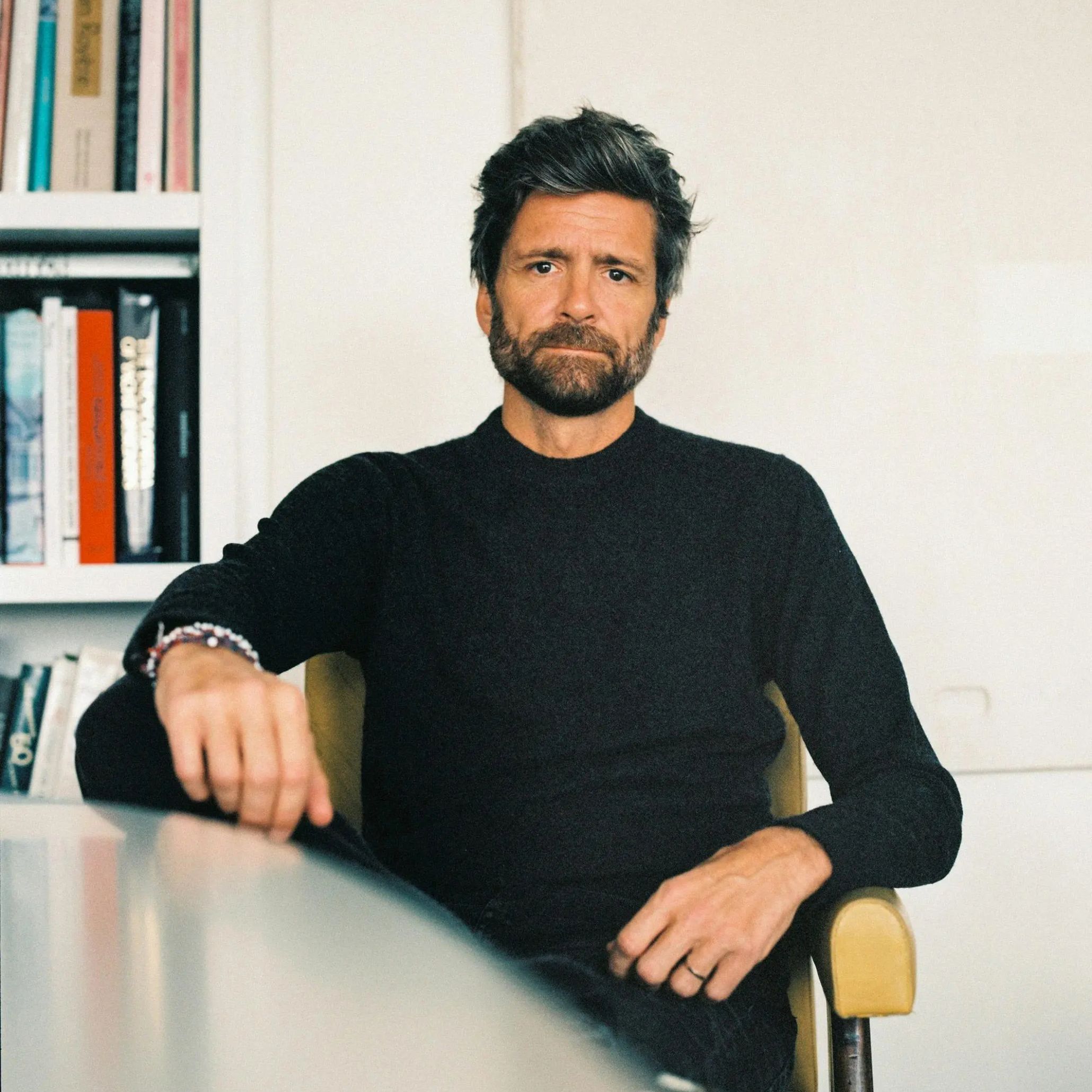 Portrait of Joseph Dirand seated in a modern interior, conveying his disciplined architectural vision and his refined sensitivity to space, volume, and the quiet precision that defines his work.