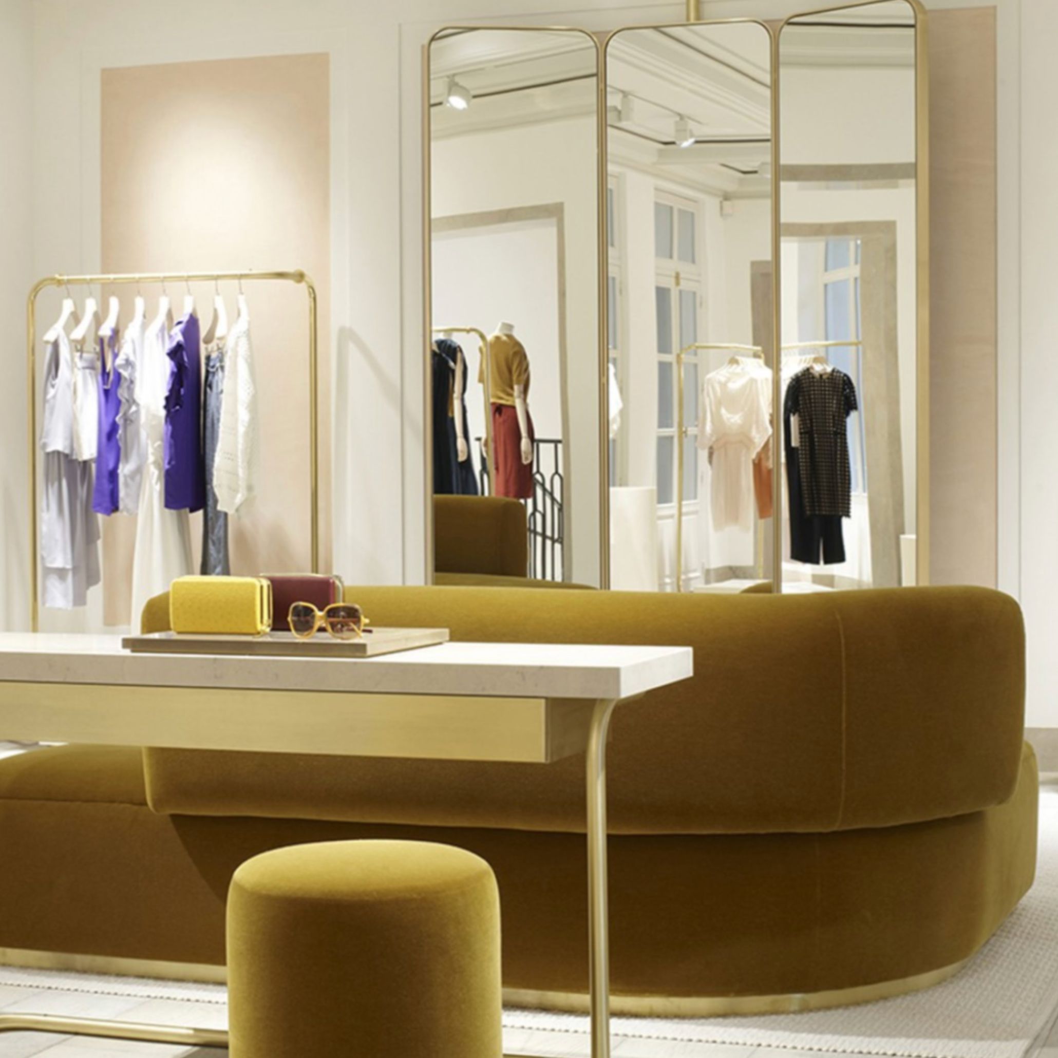 Interior of Chloé’s Saint-Honoré boutique, featuring a mustard velvet sofa, curated fashion displays, and gold accents. Joseph Dirand’s restrained design frames garments with clarity, allowing architecture and couture to coexist in a space defined by proportion, light, and material continuity.