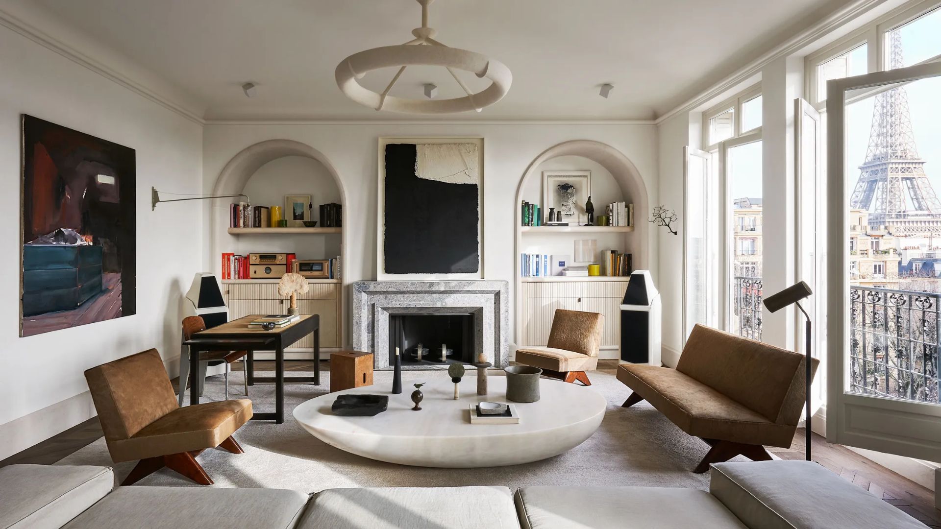 Living room from Joseph Dirand’s Alboni project in Paris, featuring sculptural furniture, a marble coffee table, and a view of the Eiffel Tower. The space reflects Dirand’s mastery of rhythm, material, and light - where stone, wood, and proportion create a quiet sense of enclosure and architectural intimacy.