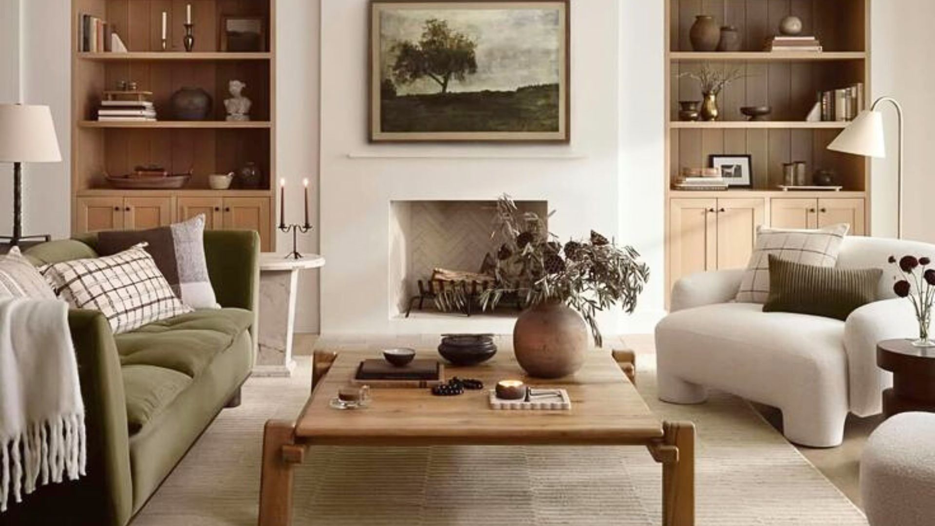 Warm Transitional living room with a moss green velvet sofa, modern white armchair, wooden coffee table, and fireplace with landscape art - featuring earthy tones, natural textures, and balanced styling that reflect the enduring comfort and quiet luxury of Transitional Design.