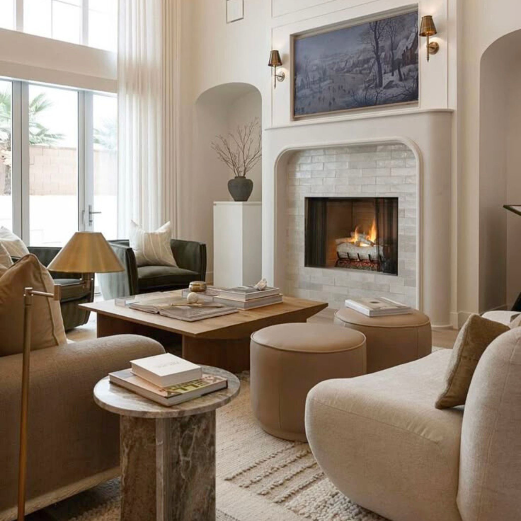 Elegant Transitional Style living room with a central fireplace, beige seating, round benhces, and arched windows - showcasing symmetry, flow, and a calm layout that supports everyday living with understated luxury.