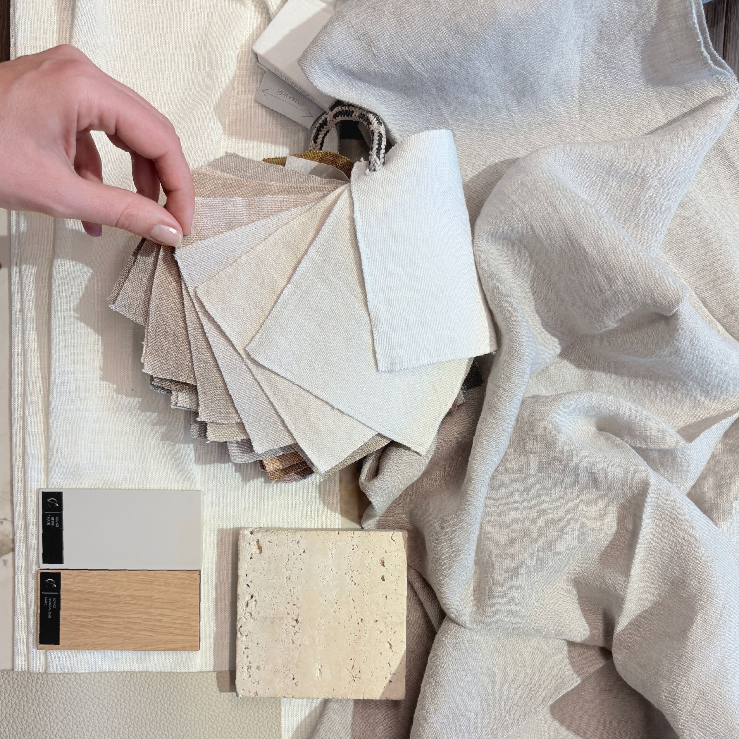 Curated selection of interior materials in soft neutral tones, including linen, travertine stone, wood finishes, and textured swatches. Arranged on a marble surface, the palette reflects Cloud Dancer’s versatility, a tactile expression of clarity and emotional balance in design.