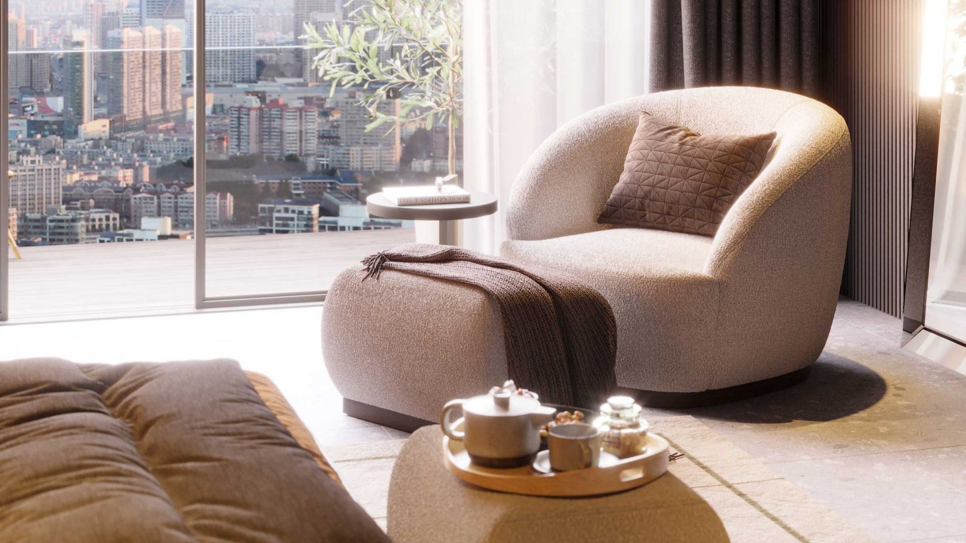 A cozy interior scene featuring the Club Armchair and matching stool, upholstered in soft bouclé and styled with a quilted pillow and textured throw. A round side table and a tray with tea and snacks complete the setting, while floor-to-ceiling windows frame a panoramic urban view. The tactile richness of bouclé reflects 2026’s trend toward materials that balance comfort, elegance, and sensory appeal.