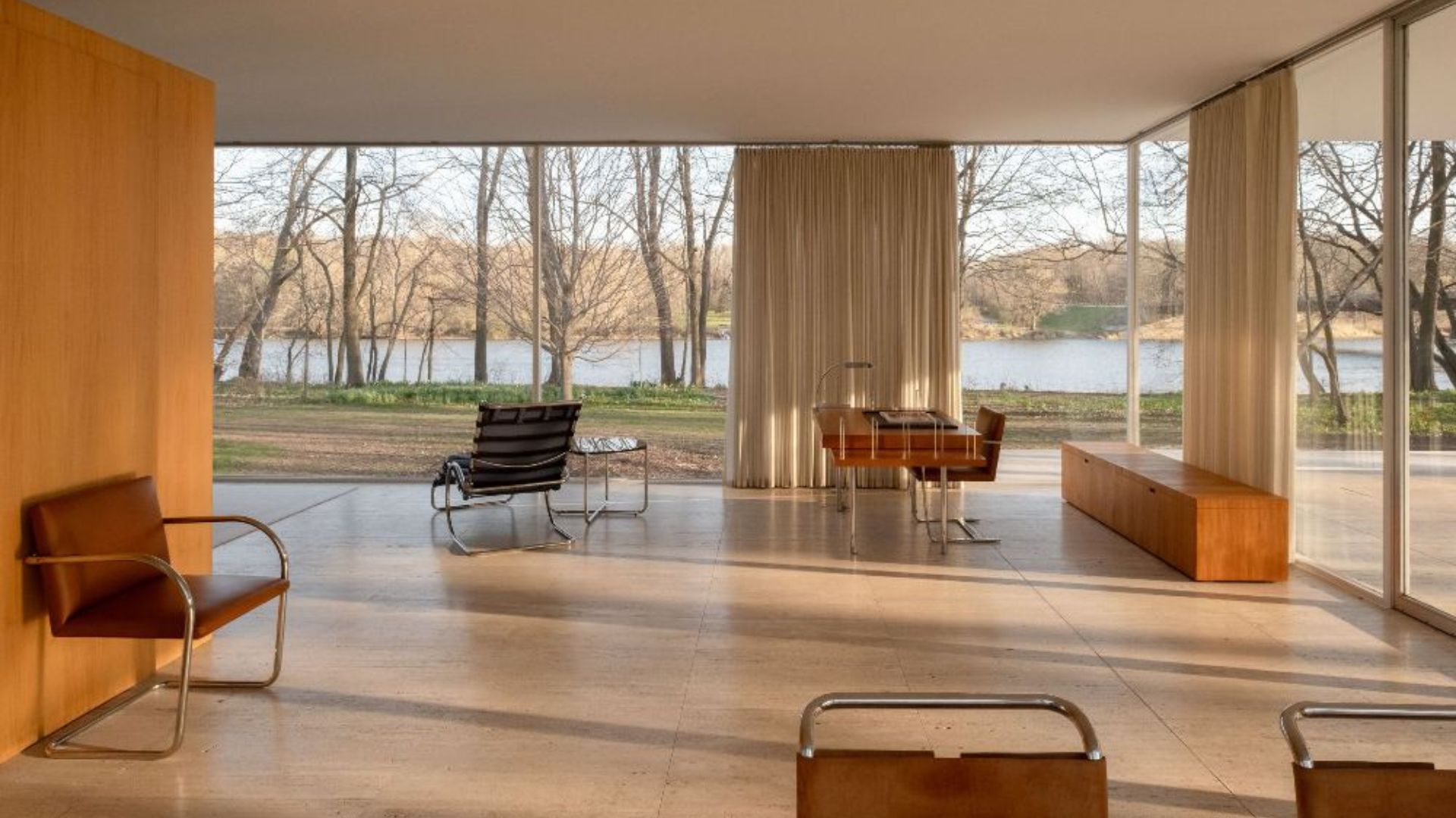 The interior of the Farnsworth House reveals an open, light‑filled space where floor‑to‑ceiling glass frames the surrounding landscape. Mid‑century pieces and custom furniture sit with deliberate restraint, showing how Mies van der Rohe used furniture placement rather than walls to define proportion and movement. The minimalist design, refined materials, and subtle design details reflect the house’s influence on luxury furniture and contemporary interior design, reinforcing its status as a benchmark for clarity and spatial discipline.