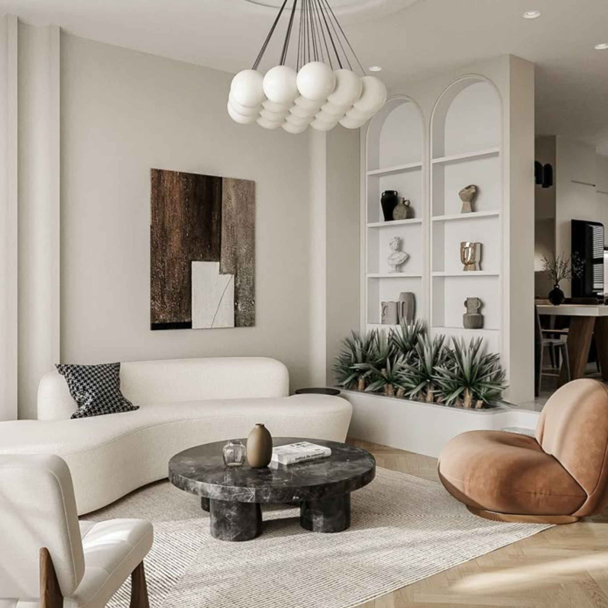 A softly lit living room featuring curved living room furniture, including a white sofa paired with a round marble coffee table and a tan accent chair. The scene reflects contemporary furniture design through its fluid lines, warm textures, and thoughtful design details. Built‑in shelves, sculptural décor, and an abstract artwork contribute to the layered interior design, creating a serene, romantic atmosphere shaped by gentle forms and harmonious materials.