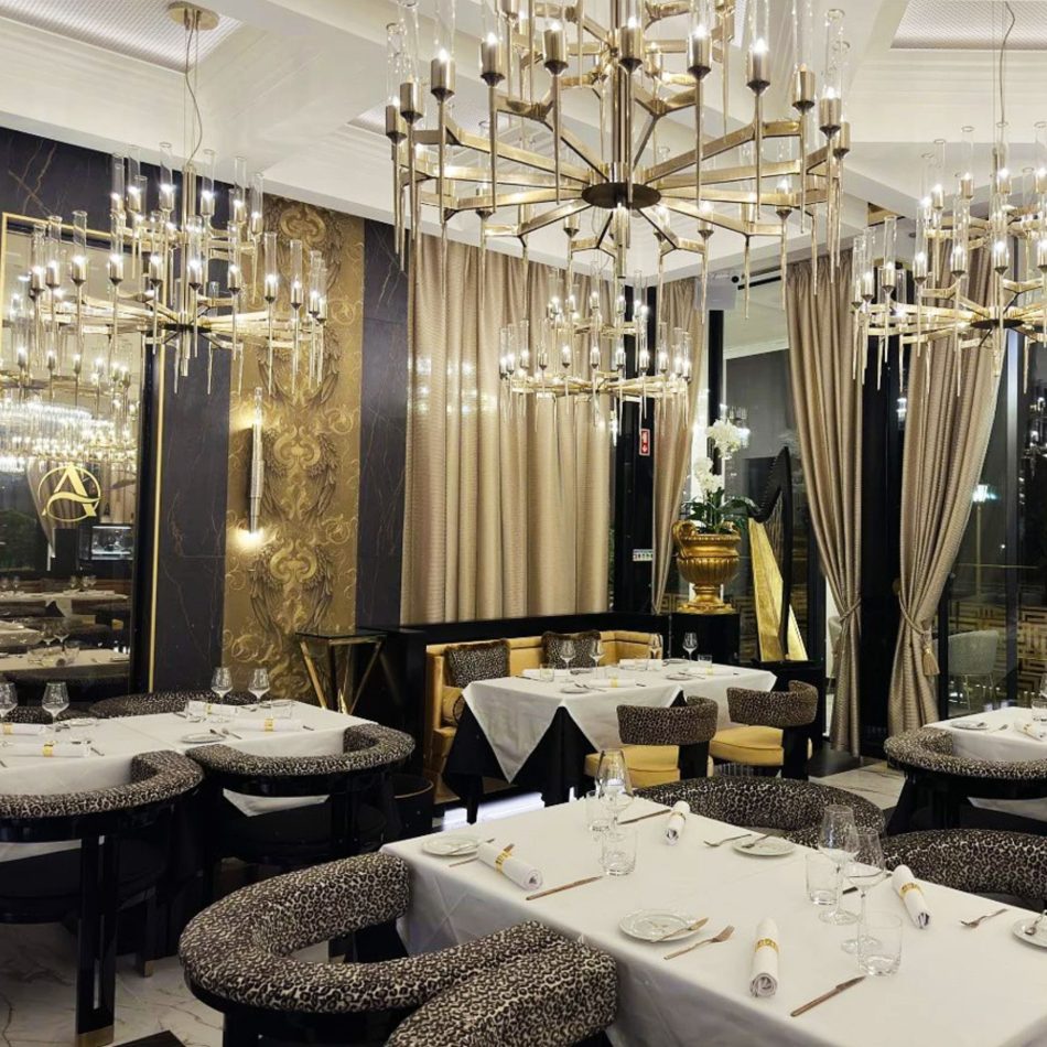 A sophisticated dining space with leopard‑patterned chairs, white table linens, and ornate chandeliers illuminating gold and marble‑inspired walls. Floral accents and tall drapery enrich the ambiance, blending restaurant Dining Chairs, elegant formal dining room furniture, curated restaurant decor ideas, warm hospitality furniture, and refined luxury furniture.