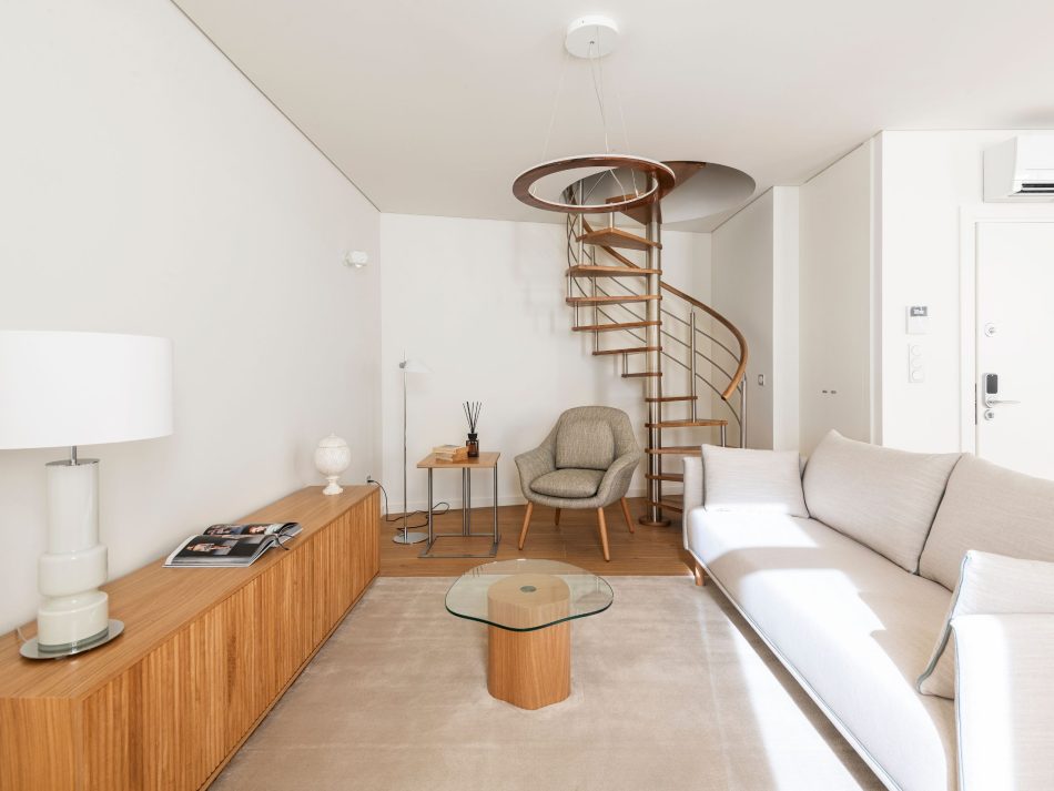 A minimalist living room where the bespoke Ryan TV Cabinet provides visual structure beneath soft natural light, complemented by the Natur Side Table and Louise Side Table that introduce intimate, functional accents. The gentle palette, warm wood, and quiet geometry create a serene atmosphere shaped by luxury living room furniture, thoughtful interior design inspiration, and the understated elegance of contemporary materials.