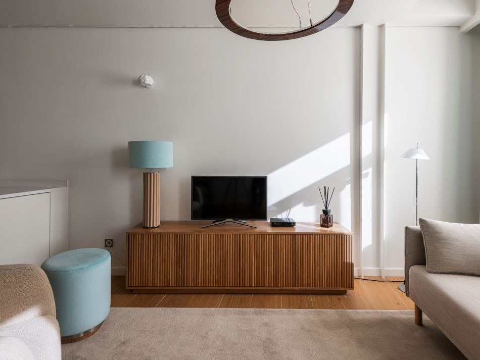 A calm corner of the guest residence where the Thomas Stool sits beside soft seating, offering a functional accent within the space. Across the room, the bespoke Ryan TV Cabinet provides quiet structure with its warm wood presence, grounding the living area in understated elegance. Gentle natural light enhances the soft palette, expressing modern furniture, refined living room design, and the serene intimacy that welcomes every guest.