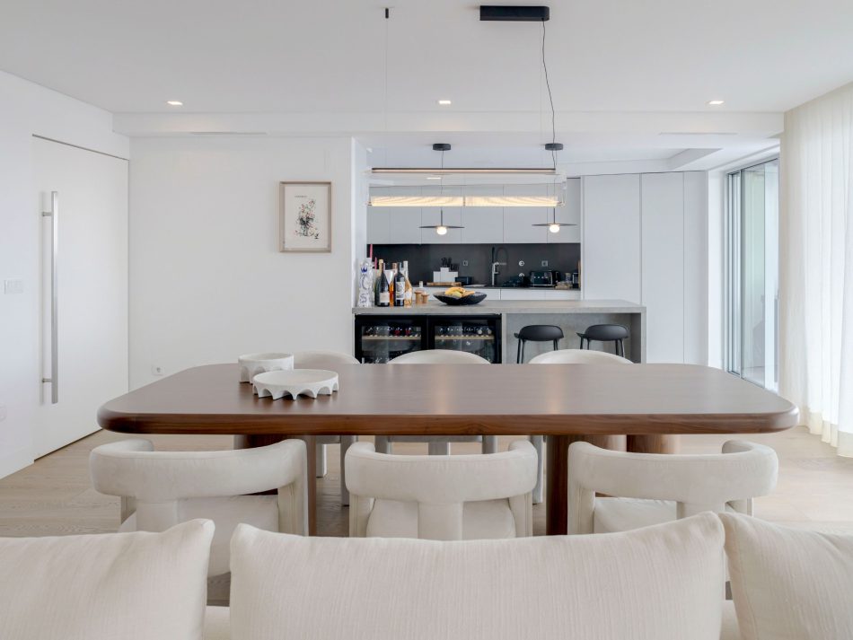 A open‑concept dining area defined by warm wood tones and a serene palette, where the Natur Dining Table becomes the focal point through its craftsmanship and organic presence. The surrounding complement its aesthetic, creating a flow between social spaces. The composition reflects modern dining table design, elevated by touches of luxury dining room furniture and the harmonious simplicity of modern furniture throughout the interior.