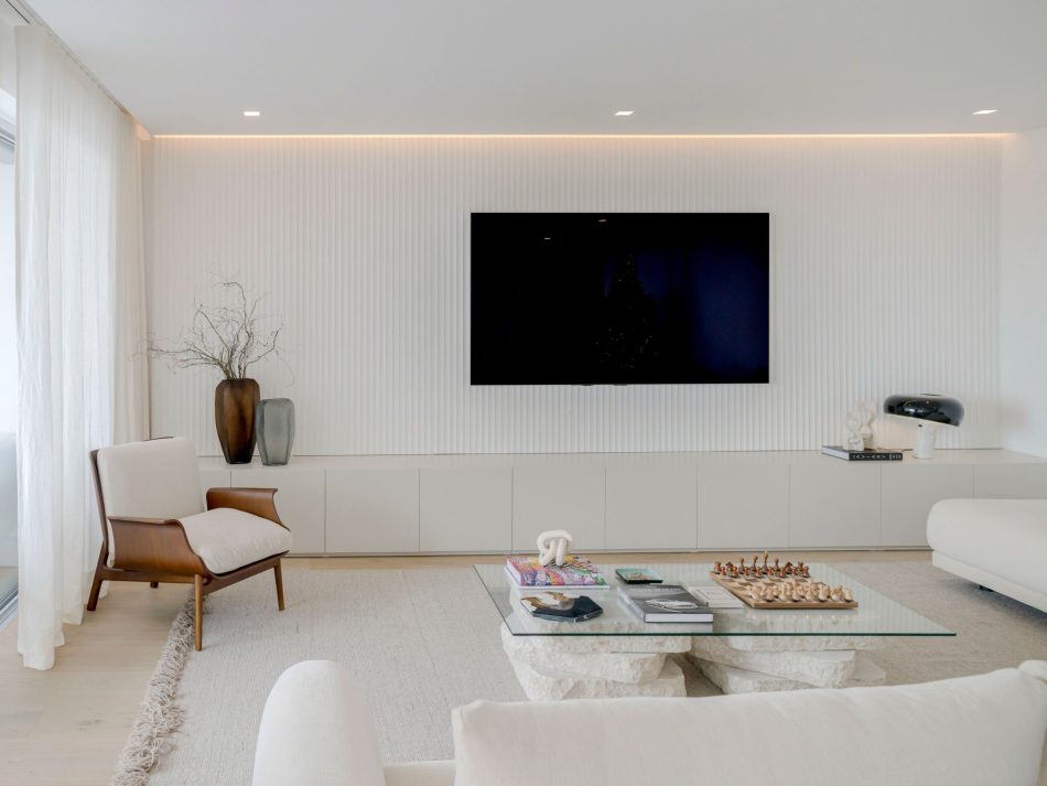 A bright open‑plan living room where natural light moves softly across textured surfaces, revealing the elegant presence of the Sevilha TV Cabinet as it anchors the space with quiet structure. The neutral palette and sculptural décor create a calm rhythm that blends bold elements of luxury home furniture with subtle touches of living room architecture, resulting in a space that feels effortlessly connected to bespoke living room design.