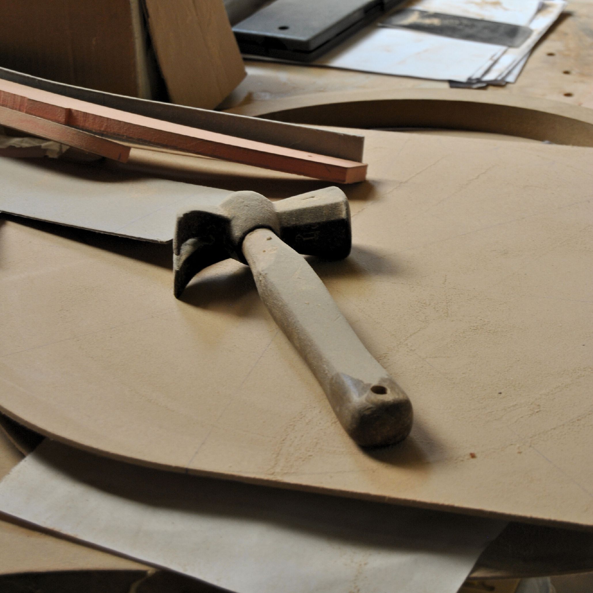Woodworking tools and timber components lie on a sawdust‑covered work surface, capturing the early production stage of the Ripa Armchair and its solid‑wood construction, reflecting the material clarity of bench made furniture, the tactile honesty of wood design, and the crafted precision found in high end furniture.