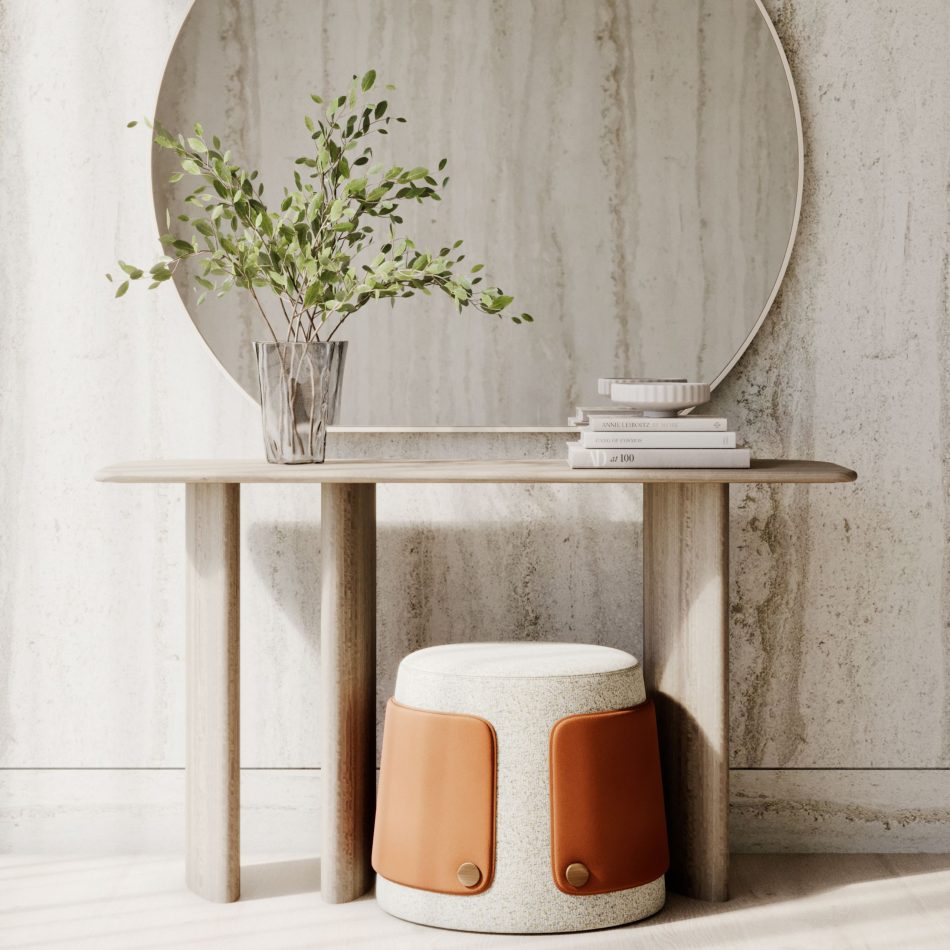 The Dolomites Stool rests quietly beneath a minimalist console table, its rounded form and leather‑and‑brass detailing bringing warmth to the soft, sunlit space. The gentle contrast between the textured fabric, natural wood, and reflective mirror creates an ambiance of tranquility, where the stool feels shaped by patience and organic flow. The scene blends natural materials and sculptural simplicity, making the stool a refined accent for entrances and modern luxury living room furniture.