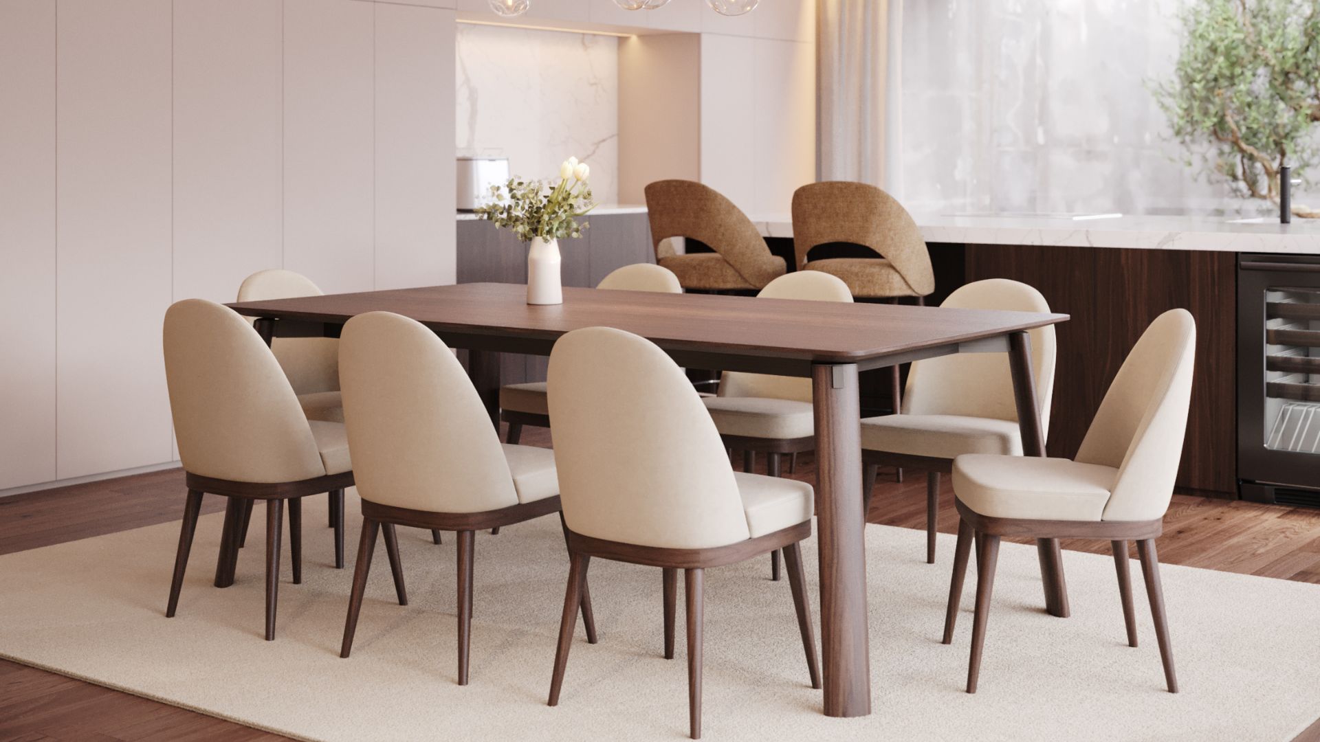 A serene modern dining room featuring the Natur Chairs, upholstered in soft neutral fabric with sculpted wooden legs that echo organic form and bespoke furniture craftsmanship. A contemporary solid‑wood dining table anchors the space, complementing the flowing lines of the Natur Collection and adding a touch of luxury dining room furniture within a calm, minimalist setting. In the background, a kitchen island with subtle modern bar chairs and refined cabinetry enhances the sense of luxury home furniture, while natural wood textures and soft light create an atmosphere of organic balance and modern design.