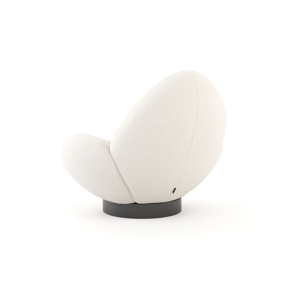 A close view of the Stone Armchair reveals its pebble‑inspired contours, plush light upholstery, and smooth transitions between seat and back, anchored by a wooden base that enhances the contrast between softness and stability, embodying the refined presence of high end furniture, the organic comfort of luxury home furniture, and the sculpted calm associated with modern living room inspiration.