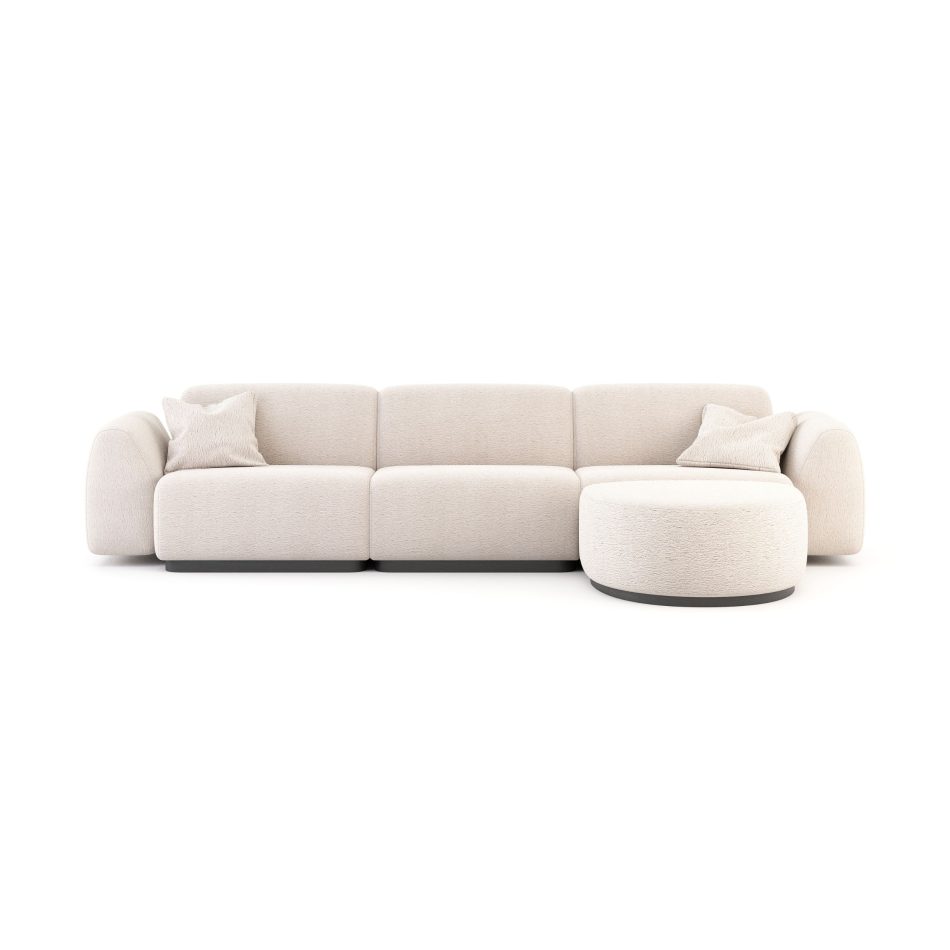 The Stone Sofa appears in a minimalist three‑piece configuration with a rounded chaise extension, upholstered in soft beige fabric with plush, sculptural cushions and matching pillows, its low‑profile silhouette creating a calm focal point within a contemporary setting subtly shaped by modern luxury furniture, thoughtful living room design, curated touches of bespoke furniture, and an inviting sense of home furniture comfort.